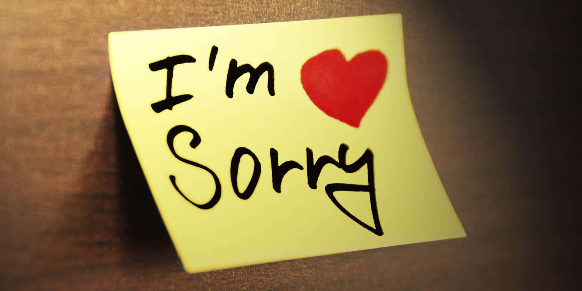 guilty 桌布 壁紙 — 一張黃色便利貼，上面有手寫的「I'm Sorry」和一個紅色心形貼紙，放在木質表面上。