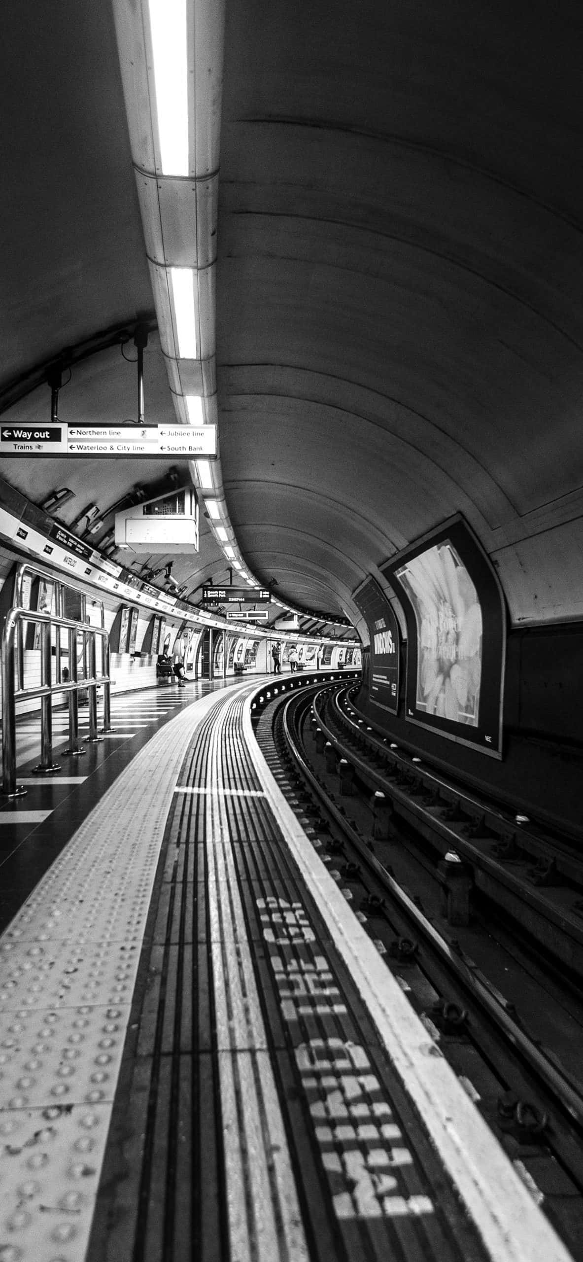 train tunnel 桌布 壁紙 — 一張黑白低角度拍攝的空蕩地鐵月台，彎曲軌道延伸入隧道。