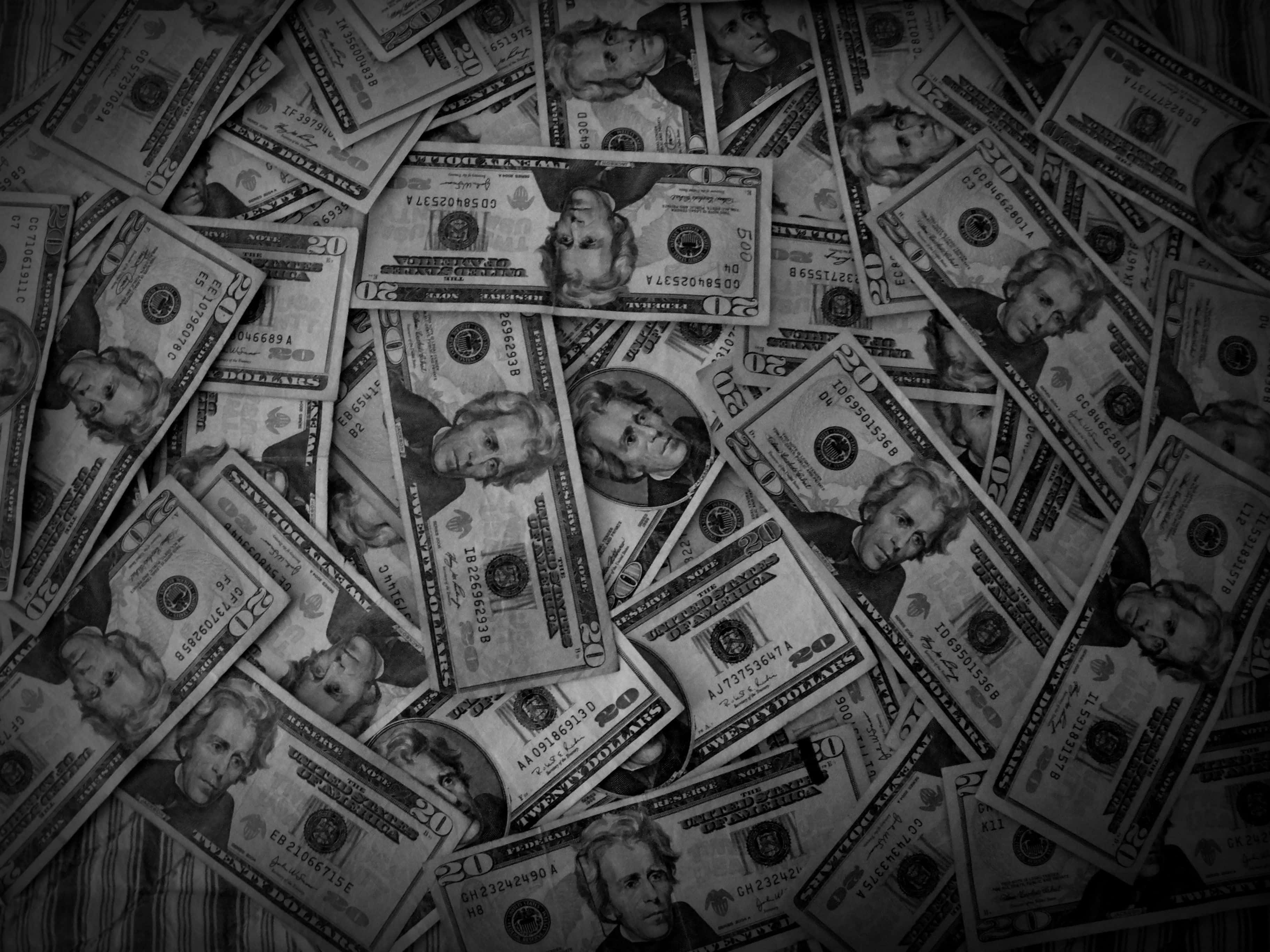 金錢 桌布 壁紙 — 一張黑白俯拍散落的二十美元鈔票，形成有紋理的金融表面。
