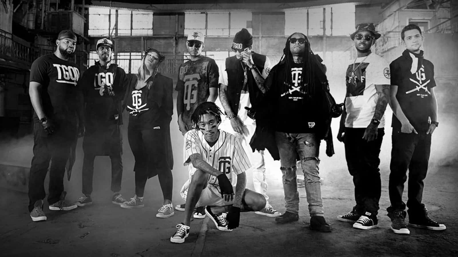 Gang 桌布 壁紙 — 一張黑白團體肖像，八位時尚打扮的嘻哈藝術家在煙霧瀰漫的工業倉庫中自信地擺姿勢。