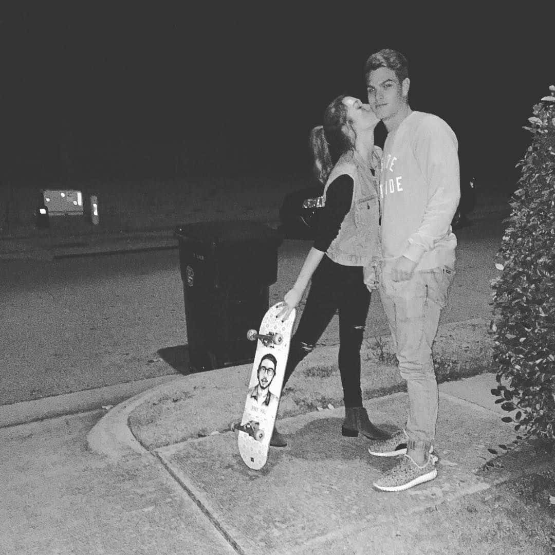 Cute Boyfriend 桌布 壁紙 — 一張黑白夜景照片，一對情侶在人行道上接吻，旁邊有一塊帶有肖像圖案的滑板。