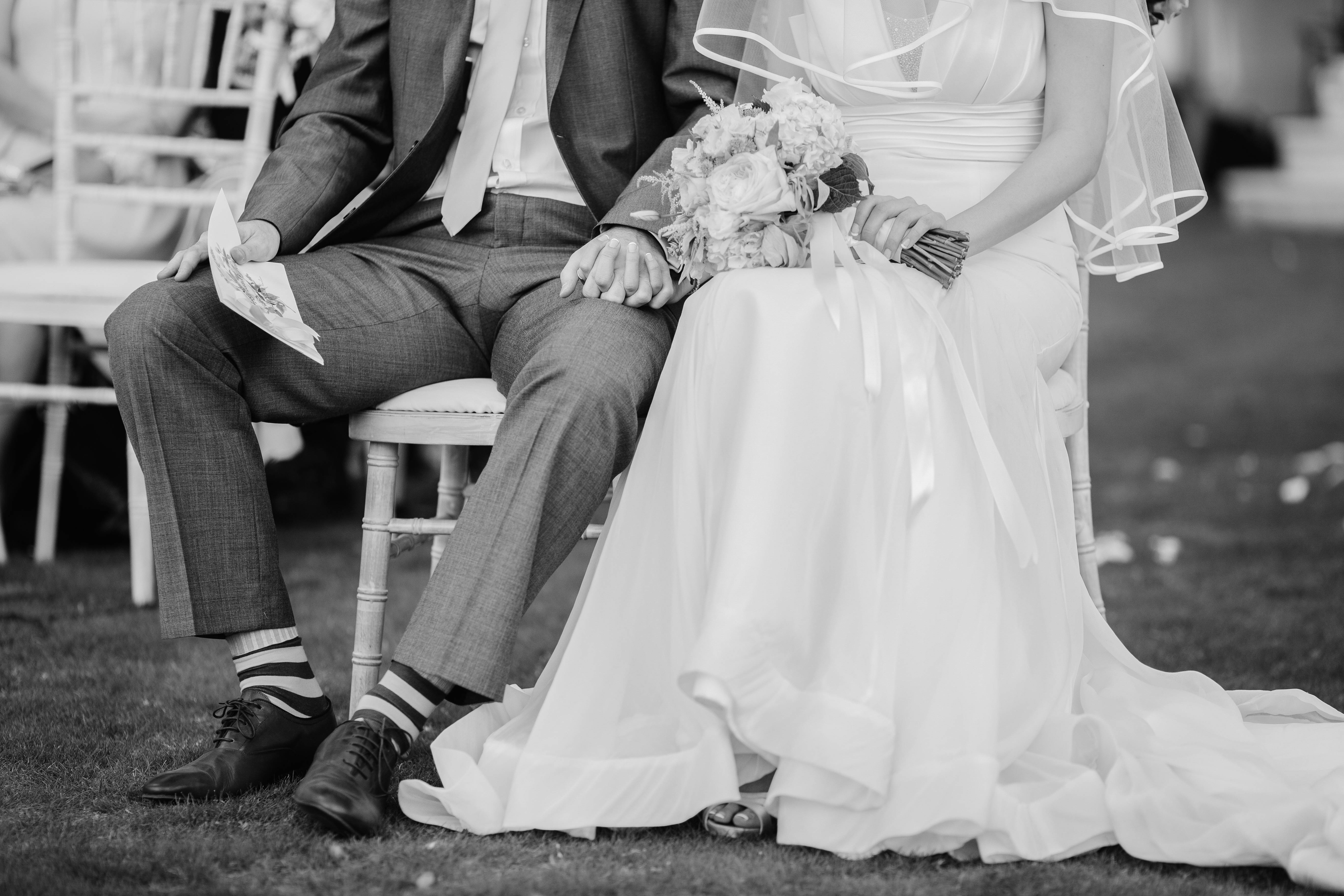 Groom 桌布 壁紙 — 一張黑白婚紗照捕捉到新娘和新郎坐在一起牽手，新娘緊握著花束。