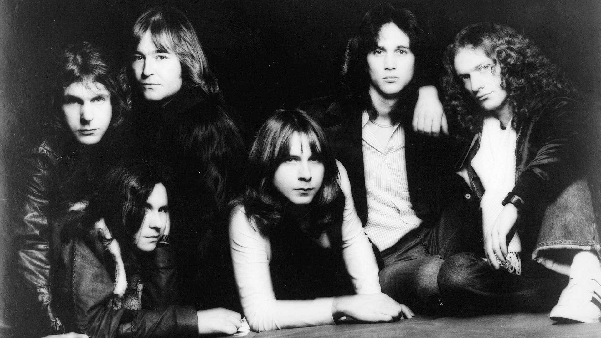 King Crimson 桌布 壁紙 — 一張黑白工作室肖像，六位長髮男性在深色背景前強烈地擺姿勢。