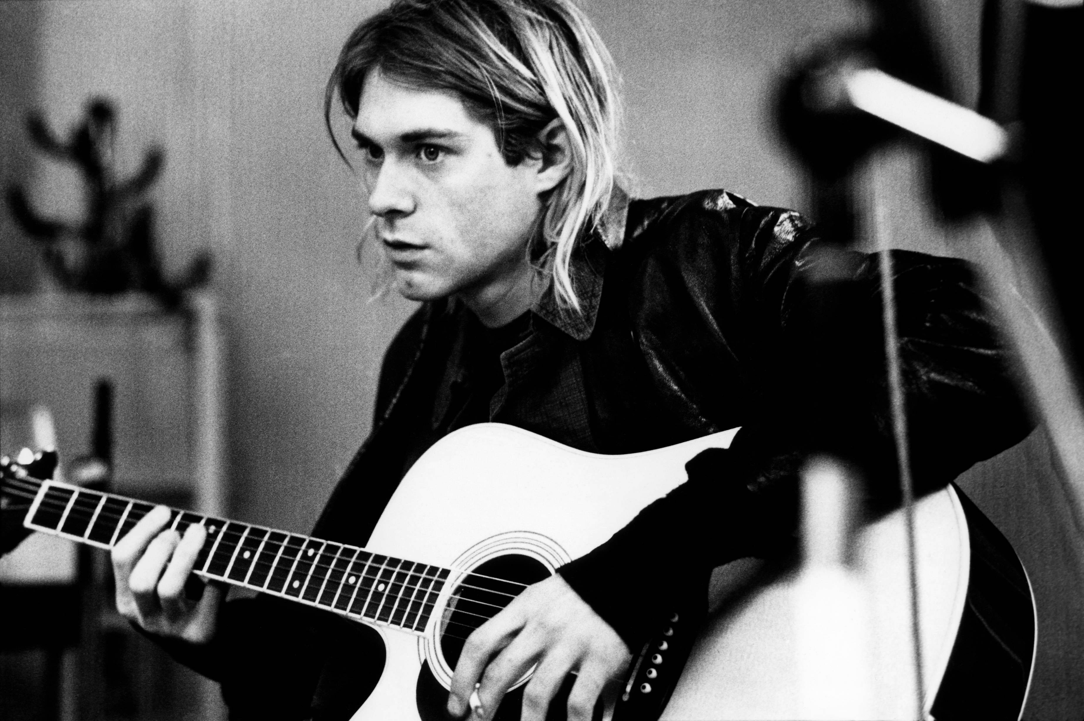 Cobain 桌布 壁紙 — 一張黑白照片，Kurt Cobain 在昏暗的房間裡激烈地彈奏木吉他。