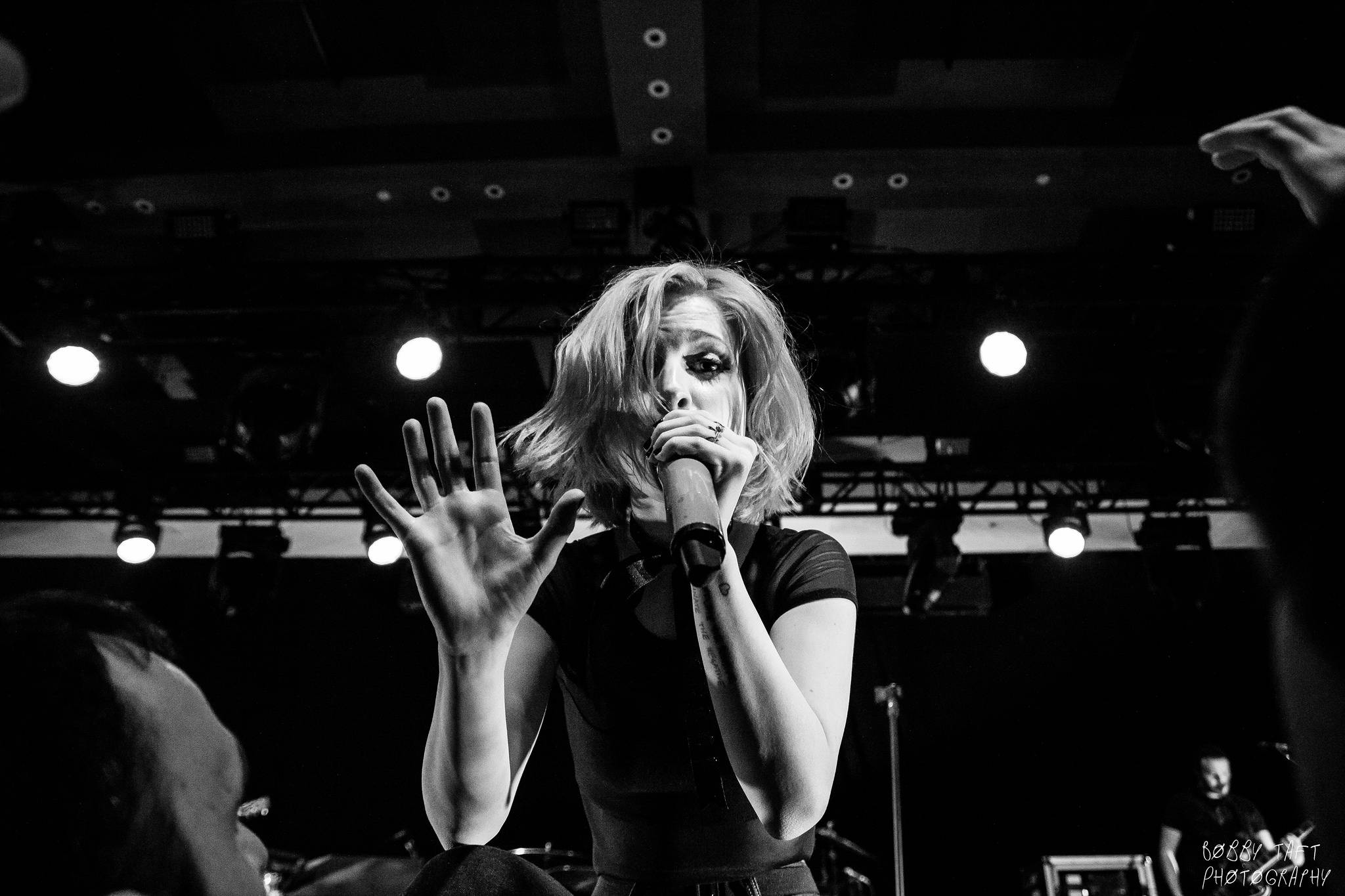 Hayley Williams 桌布 壁紙 — 一張黑白照片，一位女歌手在舞台上表演，一隻手舉起，另一隻手握著麥克風。