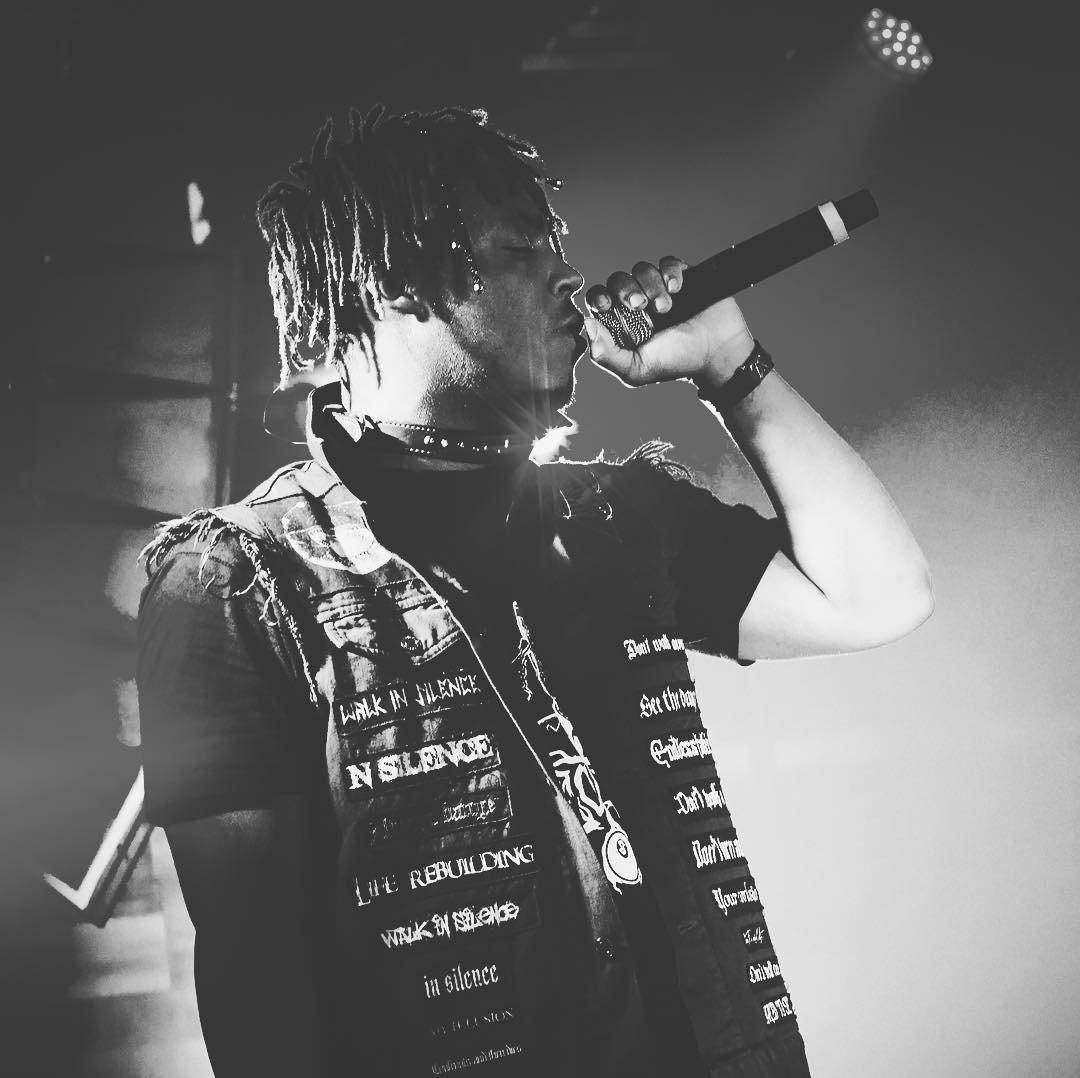 Juice Wrld Aesthetic 桌布 壁紙 — 一張黑白照片，一位梳著辮子的饒舌歌手在煙霧繚繞的舞台上，在明亮的聚光燈下對著麥克風唱歌。