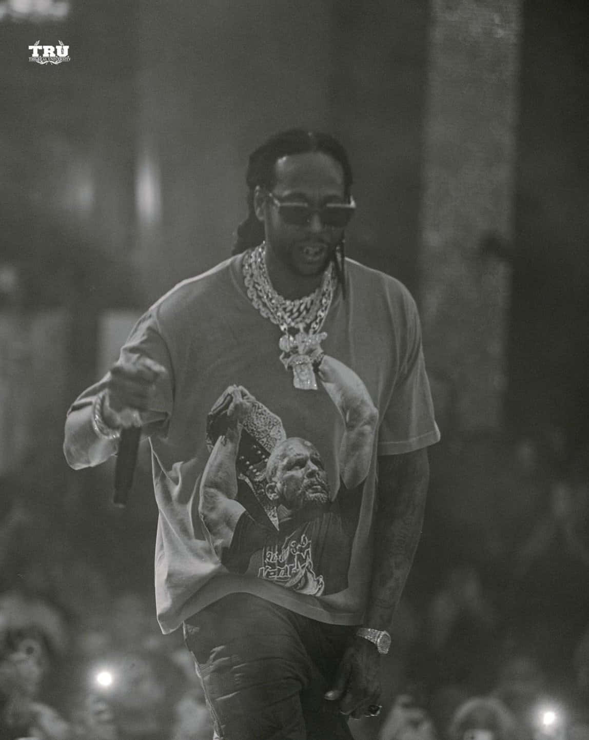 2 Chainz 桌布 壁紙 — 一張黑白照片，一位饒舌歌手在舞台上表演，戴著太陽眼鏡和圖案T恤，背景有群眾。