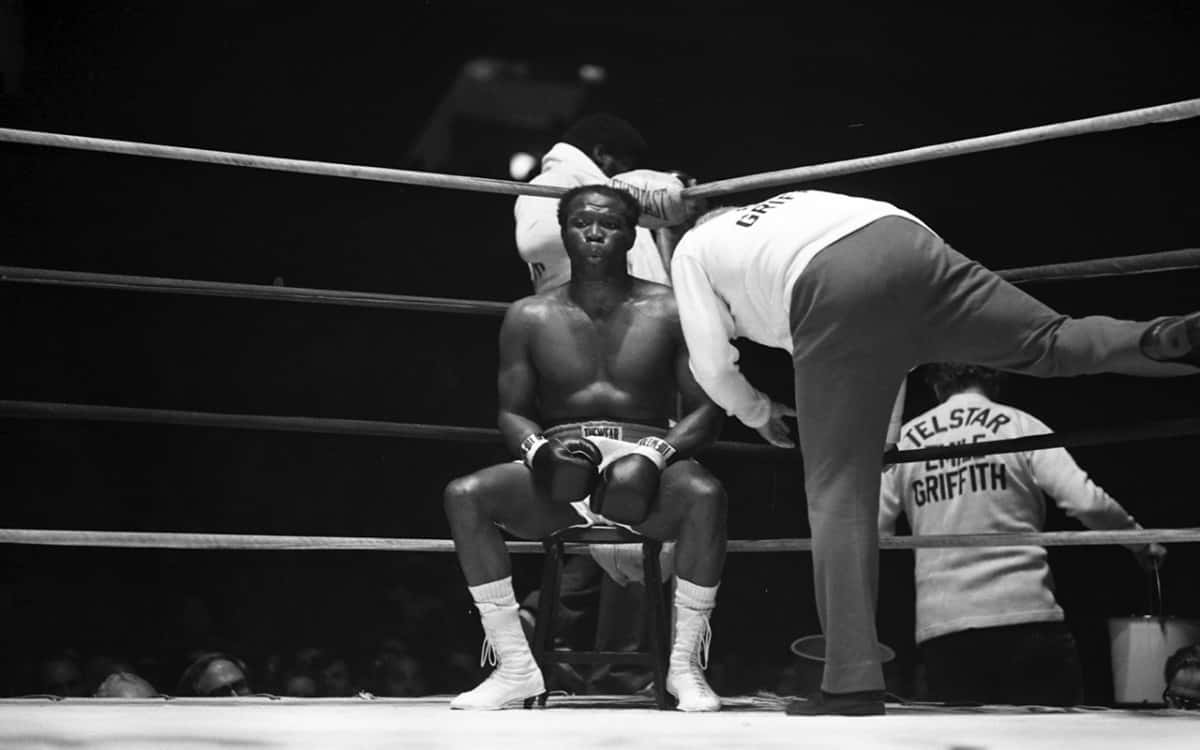 Boxing 桌布 壁紙 — 一張黑白照片，一名拳擊手坐在擂台上的凳子上，教練正在照顧他。