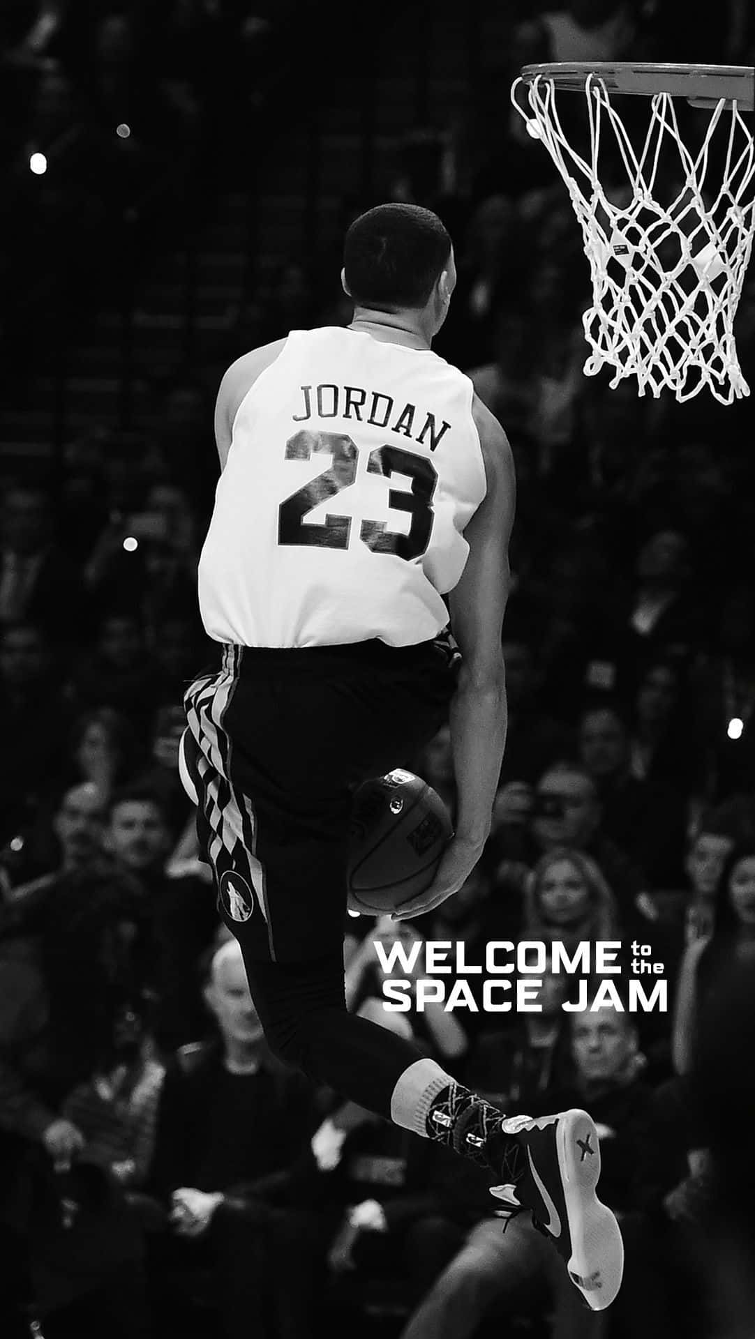 桌布 壁紙 — 一張黑白照片，一名身穿Jordan 23球衣的籃球運動員在半空中向籃框灌籃，並帶有'WELCOME to the SPACE JAM'文字。