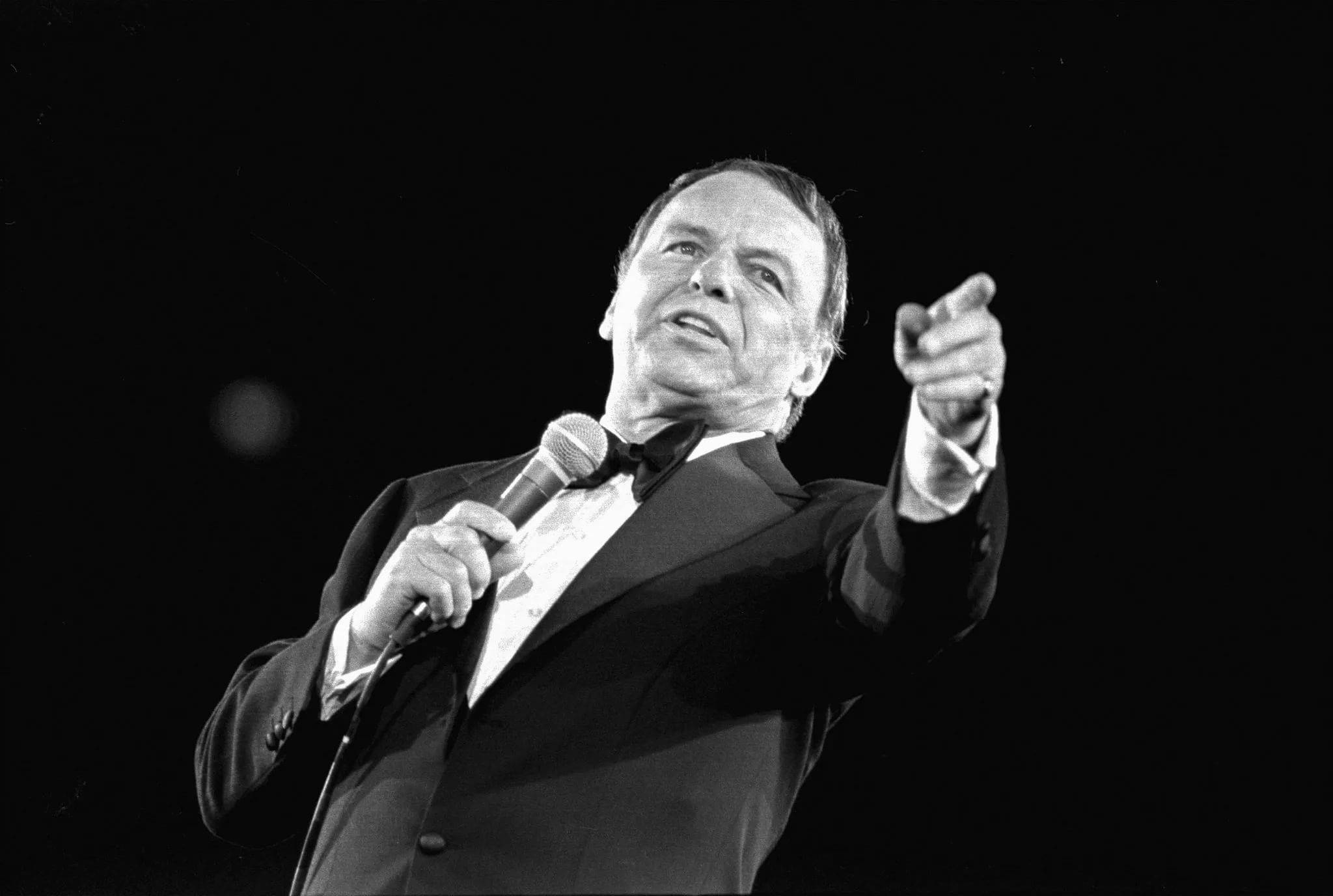 Sinatra 桌布 壁紙 — 一張黑白照片，一名身穿燕尾服的男人手持麥克風，充滿力度地向上指。