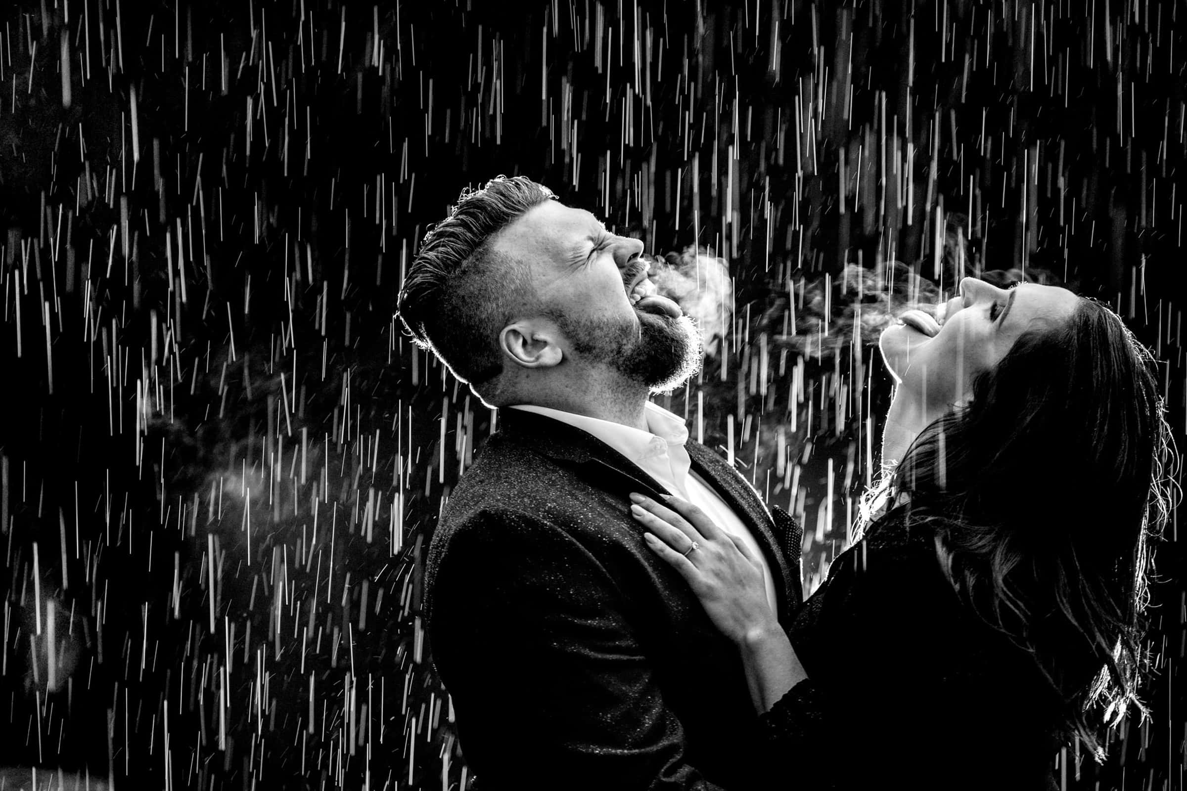 Couple In Rain 桌布 壁紙 — 一張黑白照片，一對情侶在傾盆大雨中擁抱並開懷大笑，口中冒出蒸汽。