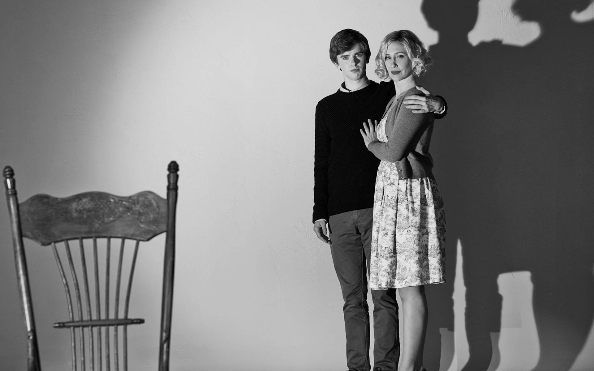 Freddie Highmore 桌布 壁紙 — 一張黑白照片，一男一女在素牆前擁抱，附近有戲劇性的陰影和一把空椅子。