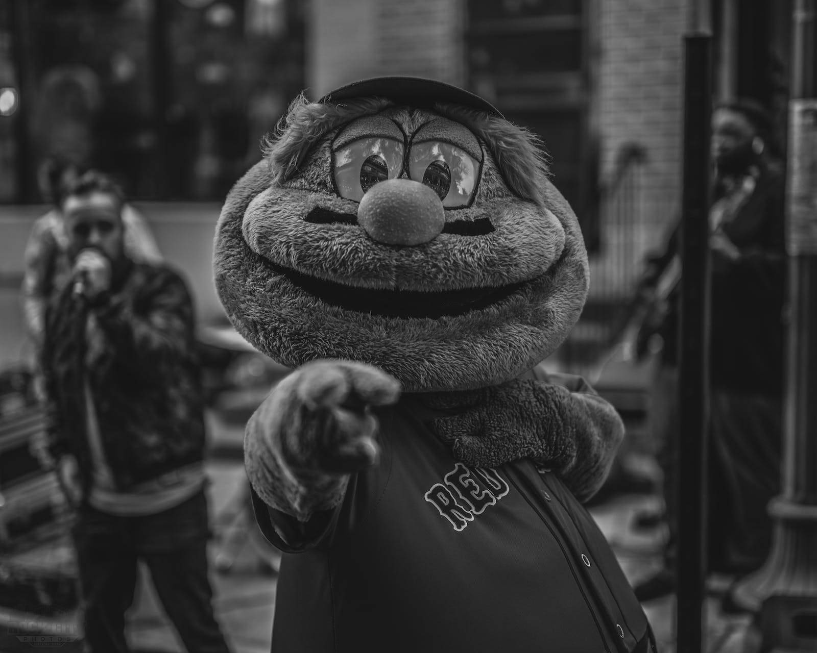 Red Sox 桌布 壁紙 — 一張黑白照片，一隻毛茸茸的吉祥物戴著帽子和「RED」球衣，在城市街道上向前指。