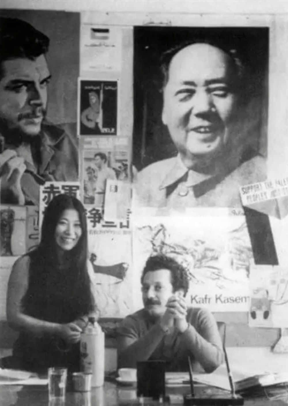 Black Panther Party 桌布 壁紙 — 一張黑白照片，兩人坐在桌旁，周圍環繞著包括毛澤東和切·格瓦拉在內的政治海報。