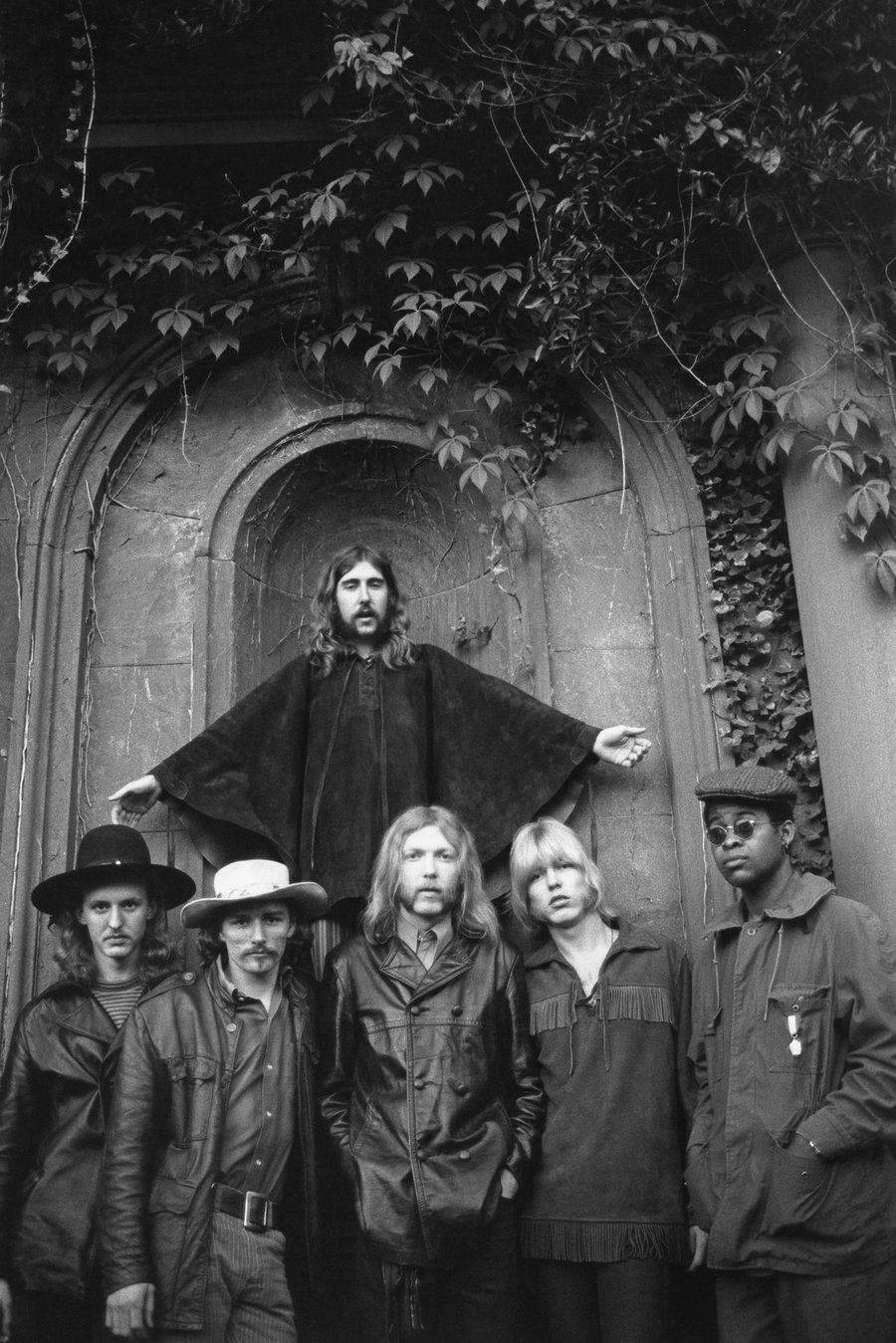 音樂 桌布 壁紙 — 一張黑白照片，六名身穿1970年代服裝的男子在常春藤覆蓋的石拱門前擺姿勢。
