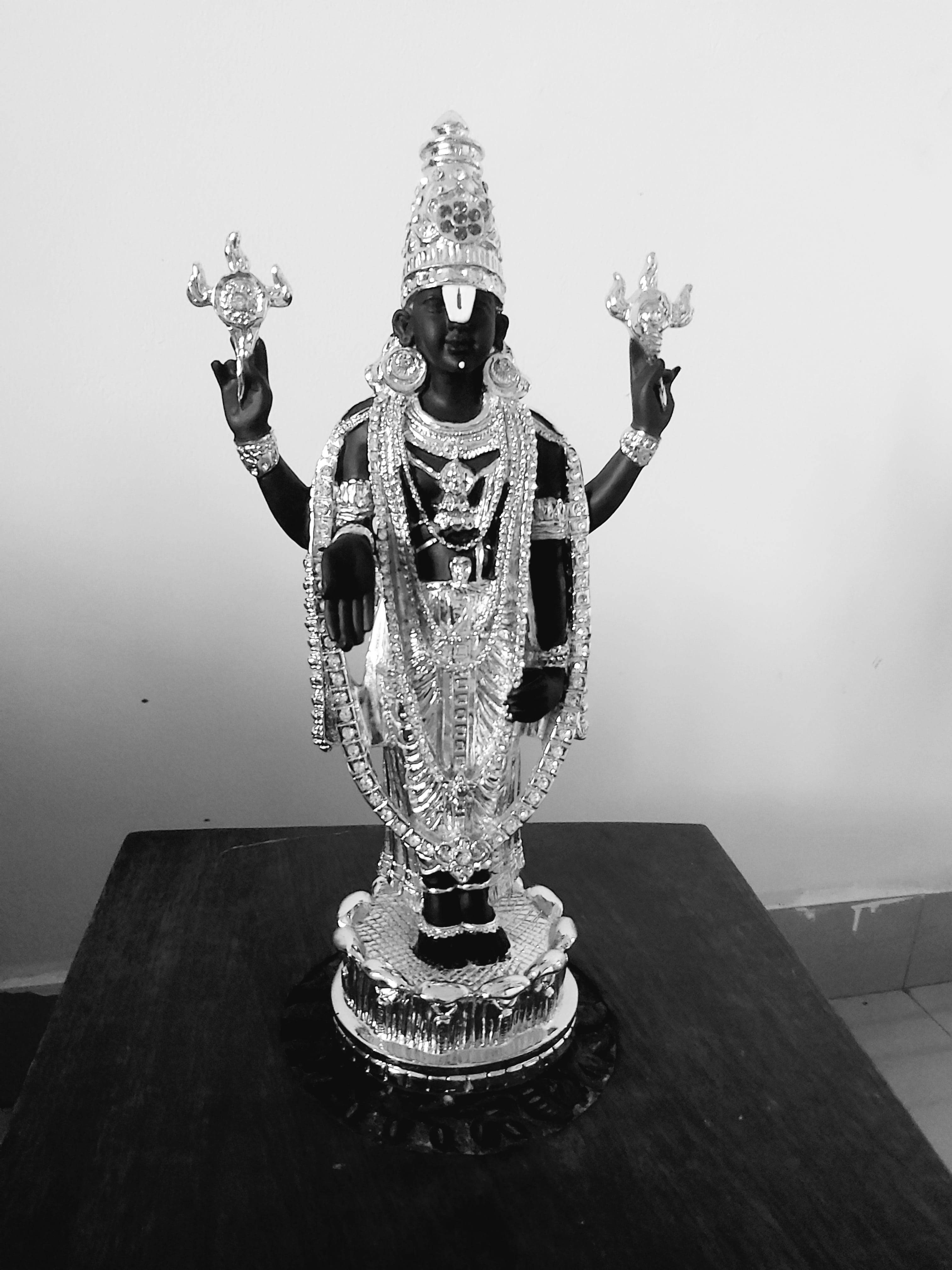 statue 桌布 壁紙 — 一張黑白照片，展示一尊裝飾華麗的銀色神像，飾有精緻珠寶，雙手高舉，立於深色木桌上。