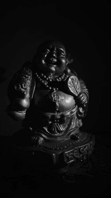 黑白微笑佛像，帶有細緻雕刻和深色背景。 — 佛陀 GIF 壁紙