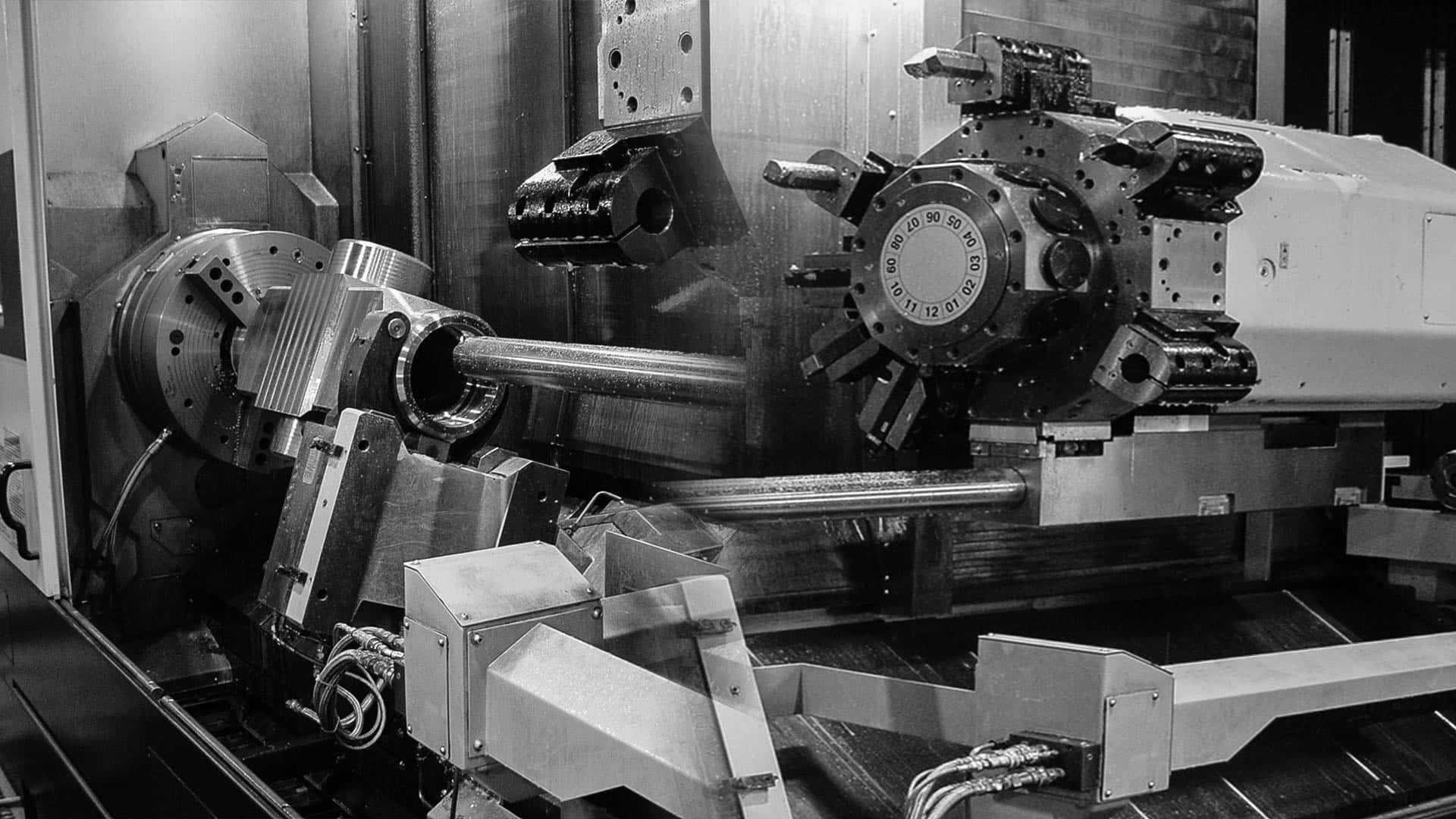 Factory 桌布 壁紙 — 一張黑白照片，展示重型工業車床在工廠環境中精確加工金屬棒。