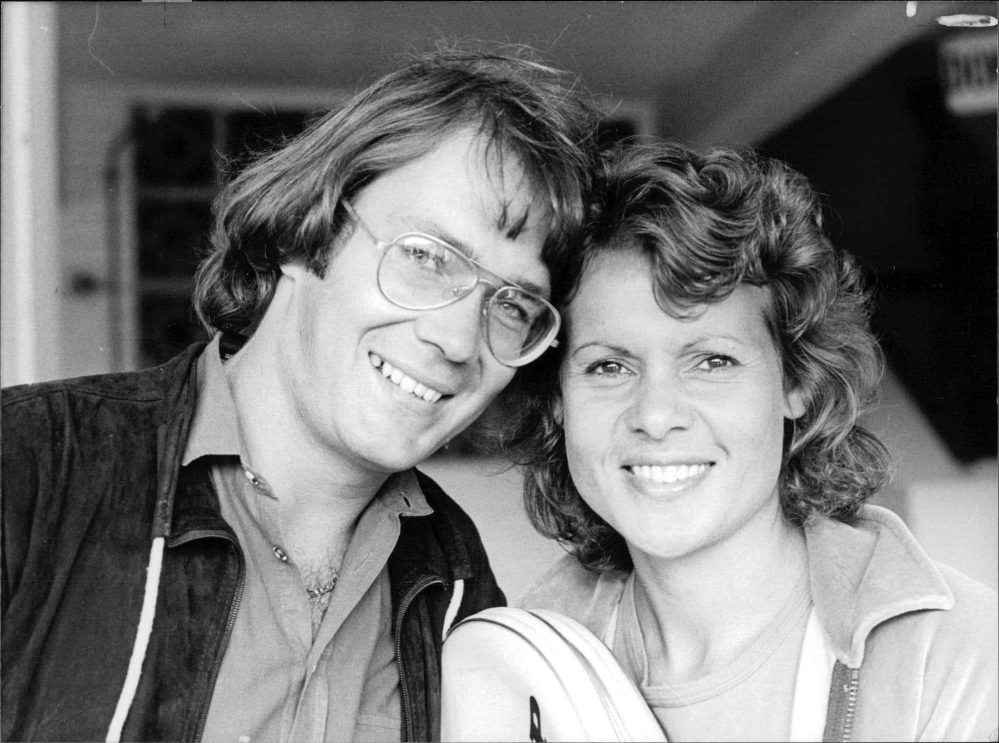 Athlete 桌布 壁紙 — 一張黑白照片，戴眼鏡的微笑男子和捲髮女子緊靠在一起。