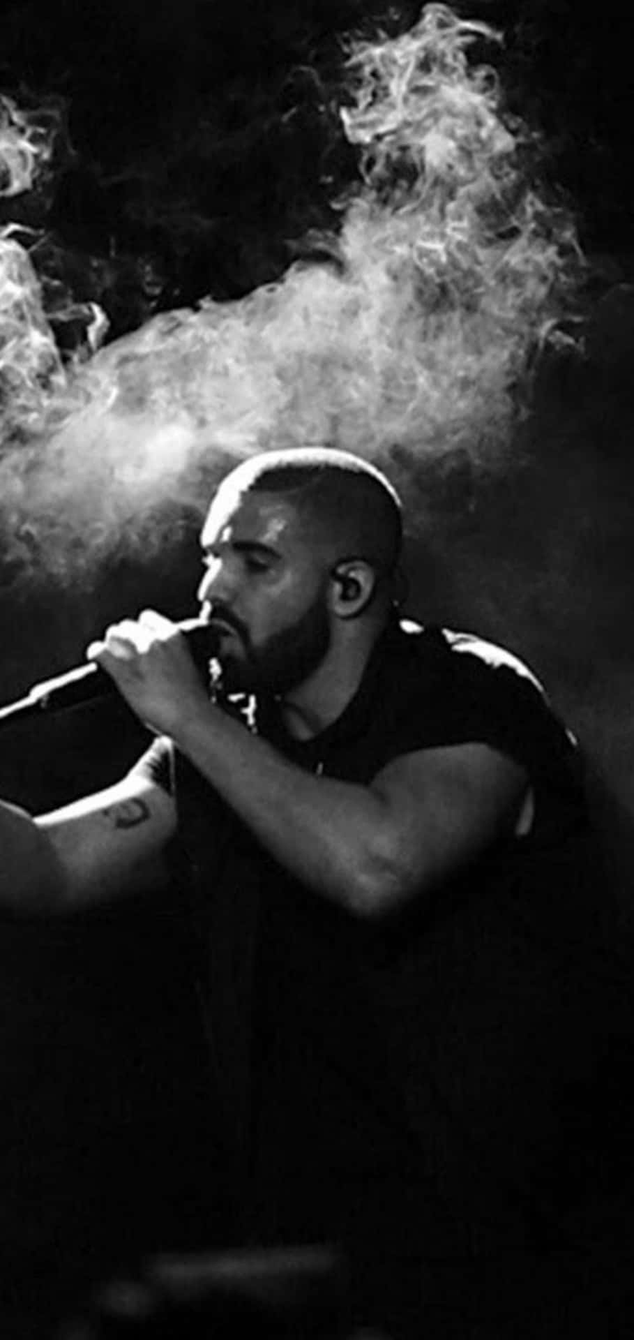 Aesthetic Drake 桌布 壁紙 — 一張黑白照片，拍攝一名留鬍鬚的男子對著麥克風唱歌，身後煙霧戲劇性地旋轉。