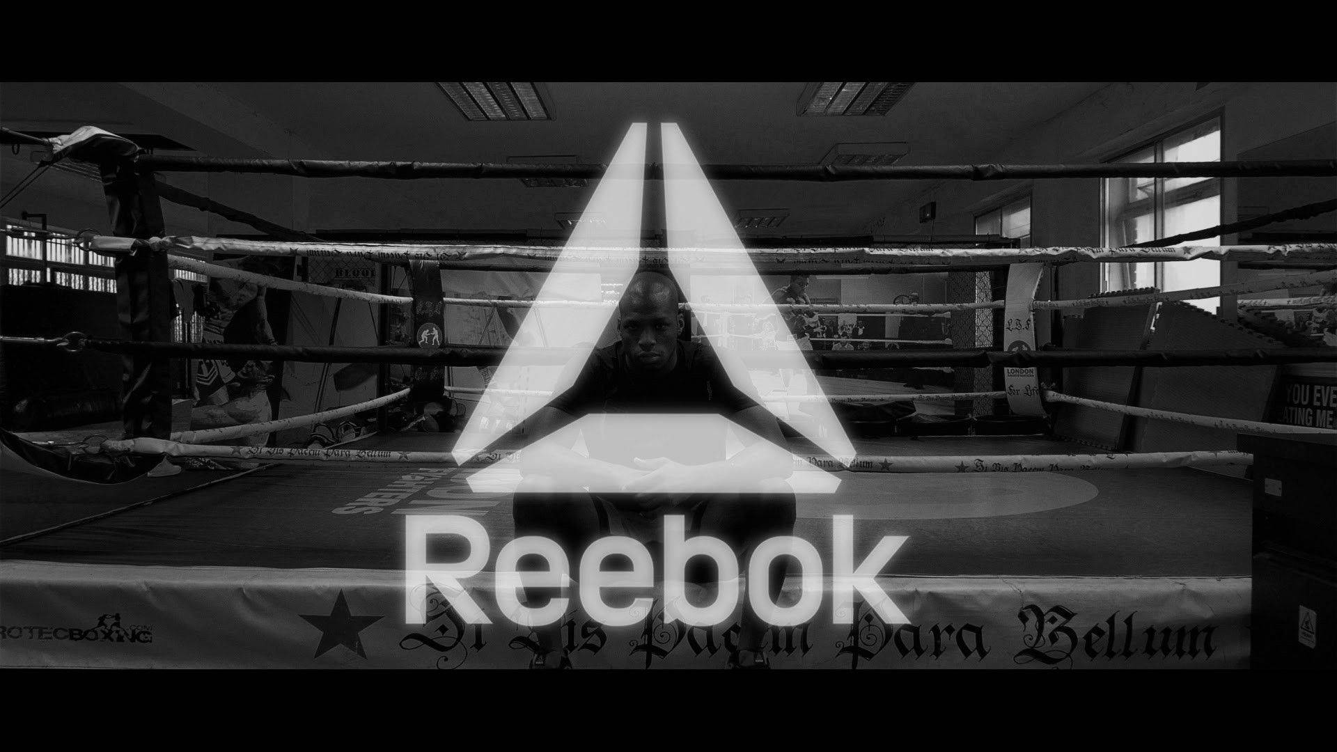 Reebok 桌布 壁紙 — 一張黑白照片，拳擊手在擂台上，帶有發光的Reebok標誌疊加。