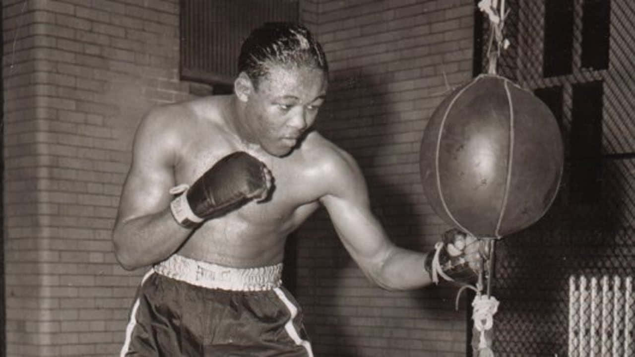 Boxing 桌布 壁紙 — 一張黑白照片，顯示一位肌肉發達的拳擊手在訓練中，對著磚牆擊打重型沙包。