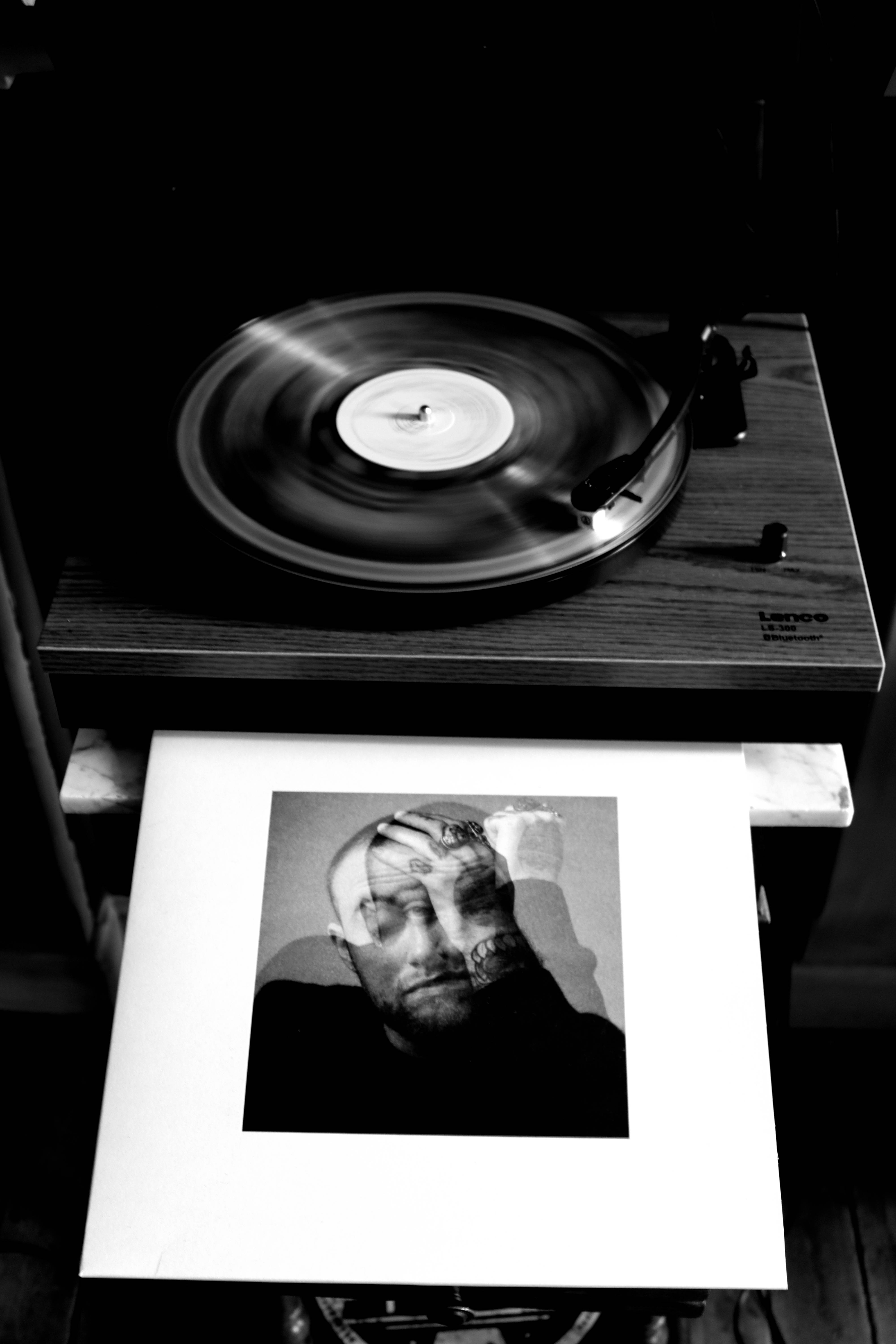 Mac Miller 桌布 壁紙 — 一張黑白照片，顯示一張旋轉的黑膠唱片放在木質唱盤上，下方有一張肖像專輯封面。