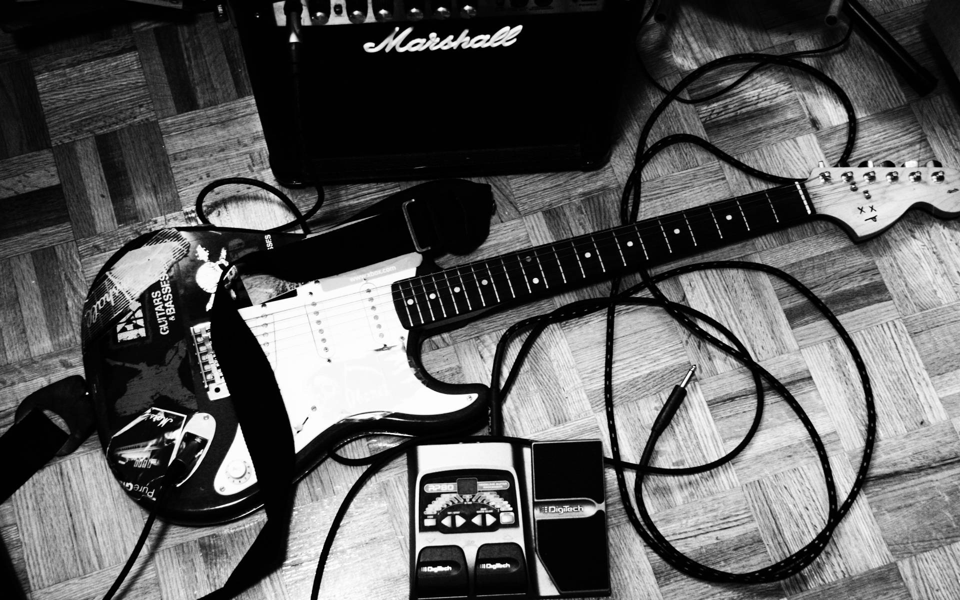 Marshall 桌布 壁紙 — 一張黑白照片，顯示一把電吉他、Marshall音箱和效果器板放在木地板上。