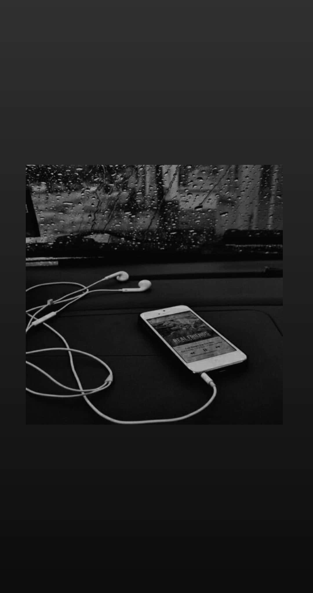 Aesthetic Music 桌布 壁紙 — 一張黑白照片，顯示智慧型手機和耳機放在汽車儀表板上，後方車窗有雨滴流過。