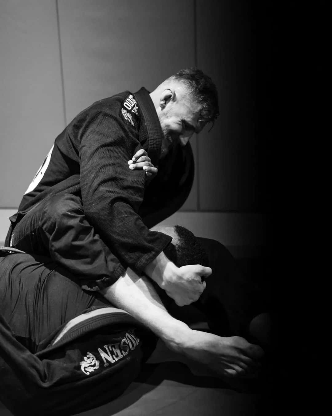 Fight 桌布 壁紙 — 一張黑白照片捕捉到一位武術家在墊子上以纏鬥姿勢壓制對手。