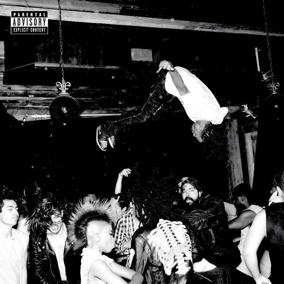 Carti 桌布 壁紙 — 一張黑白照片捕捉到一個人在昏暗的地下場地中，在龐克搖滾人群上方翻騰的瞬間。