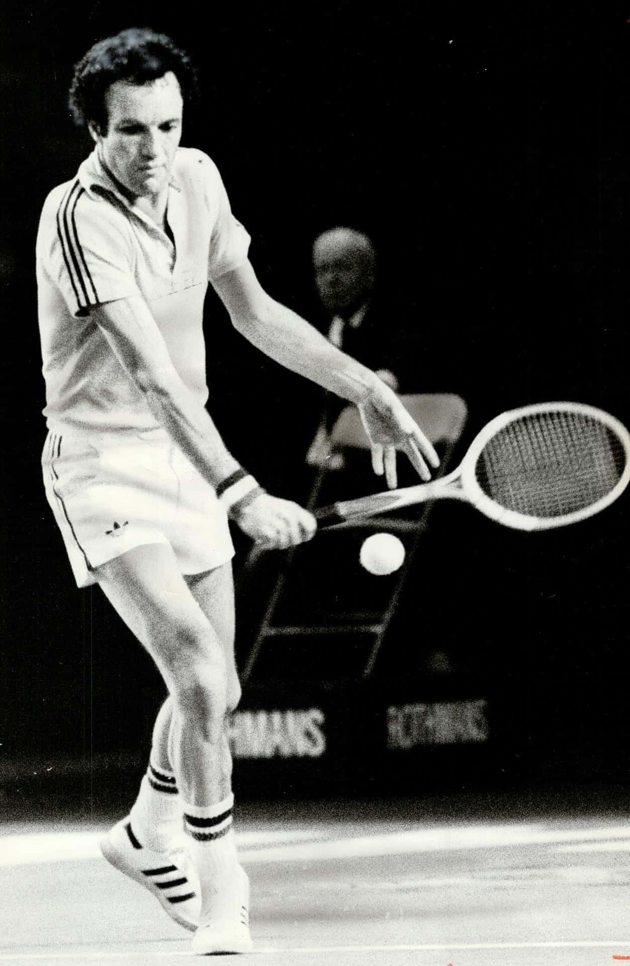 Tennis 桌布 壁紙 — 一張黑白照片捕捉到一名男網球選手在室內比賽中，以高度專注揮拍擊球的中間動作。