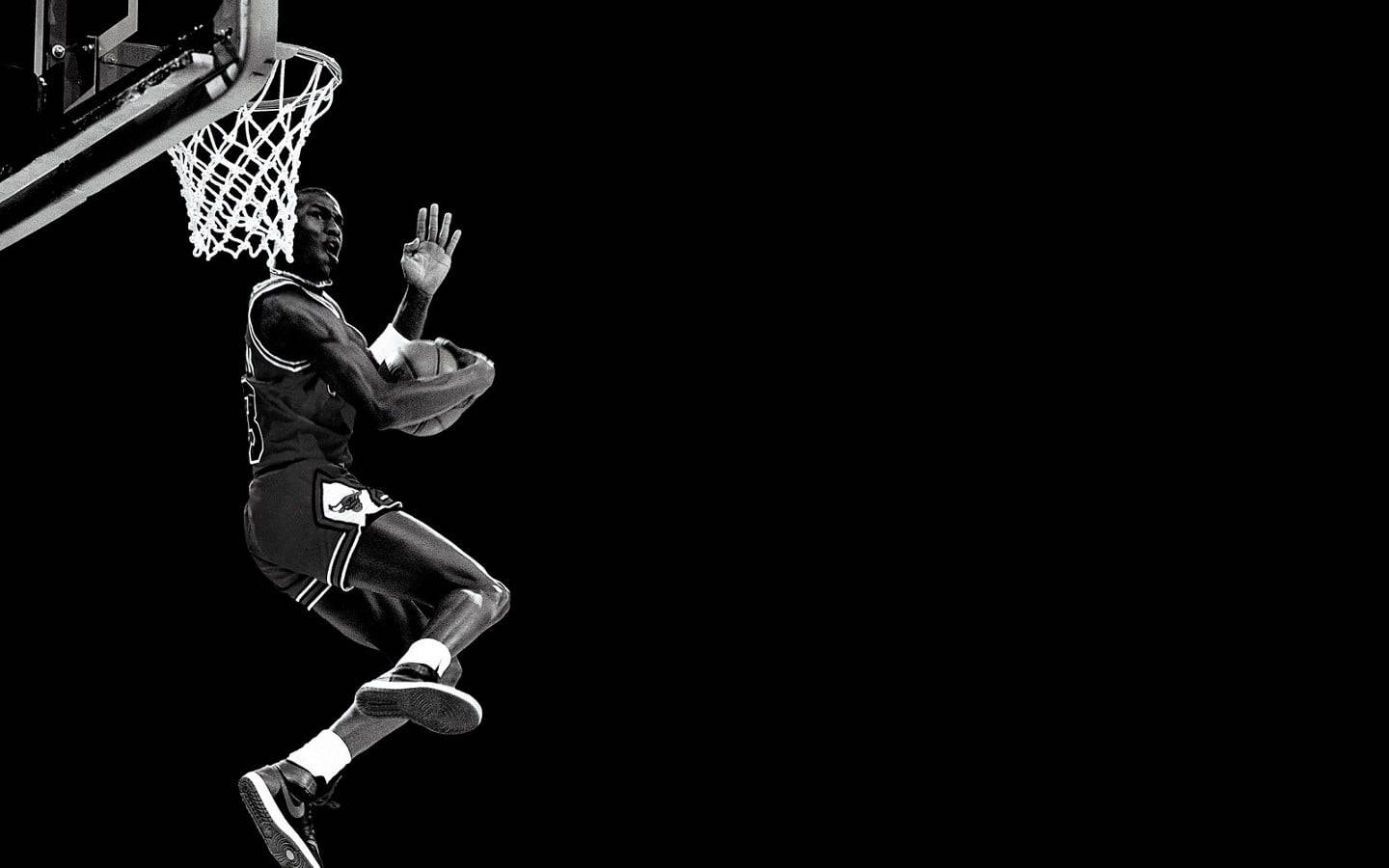 Nike iPhone 桌布 壁紙 — 一張黑白照片捕捉到一名籃球運動員在半空中扣籃，專注力極強，背景為純黑色。