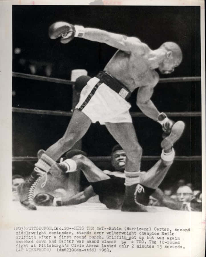 Newspaper 桌布 壁紙 — 一張黑白照片捕捉到拳擊手 Rubin Carter 在1963年的一場比賽中，在拳擊台上勝利地站在倒下的對手 Ray Griffith 上方。