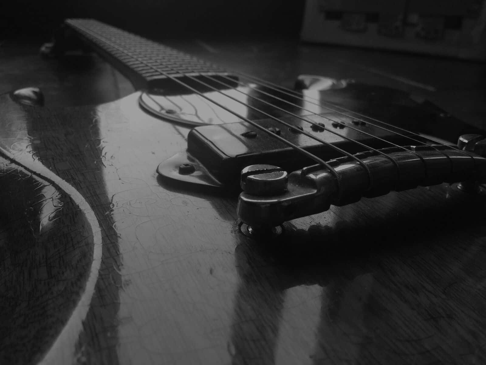 Guitar Aesthetic 桌布 壁紙 — 一張黑白特寫，展示一把復古電吉他的琴橋和琴弦擱在木質表面上。