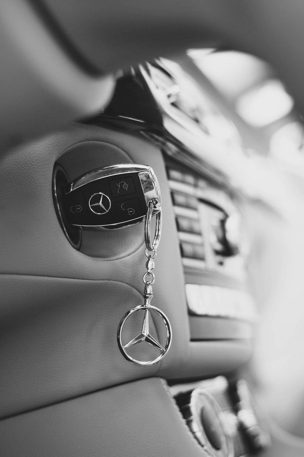 key 桌布 壁紙 — 一張黑白特寫，顯示一個賓士車鑰匙遙控器掛在車內門把手上。