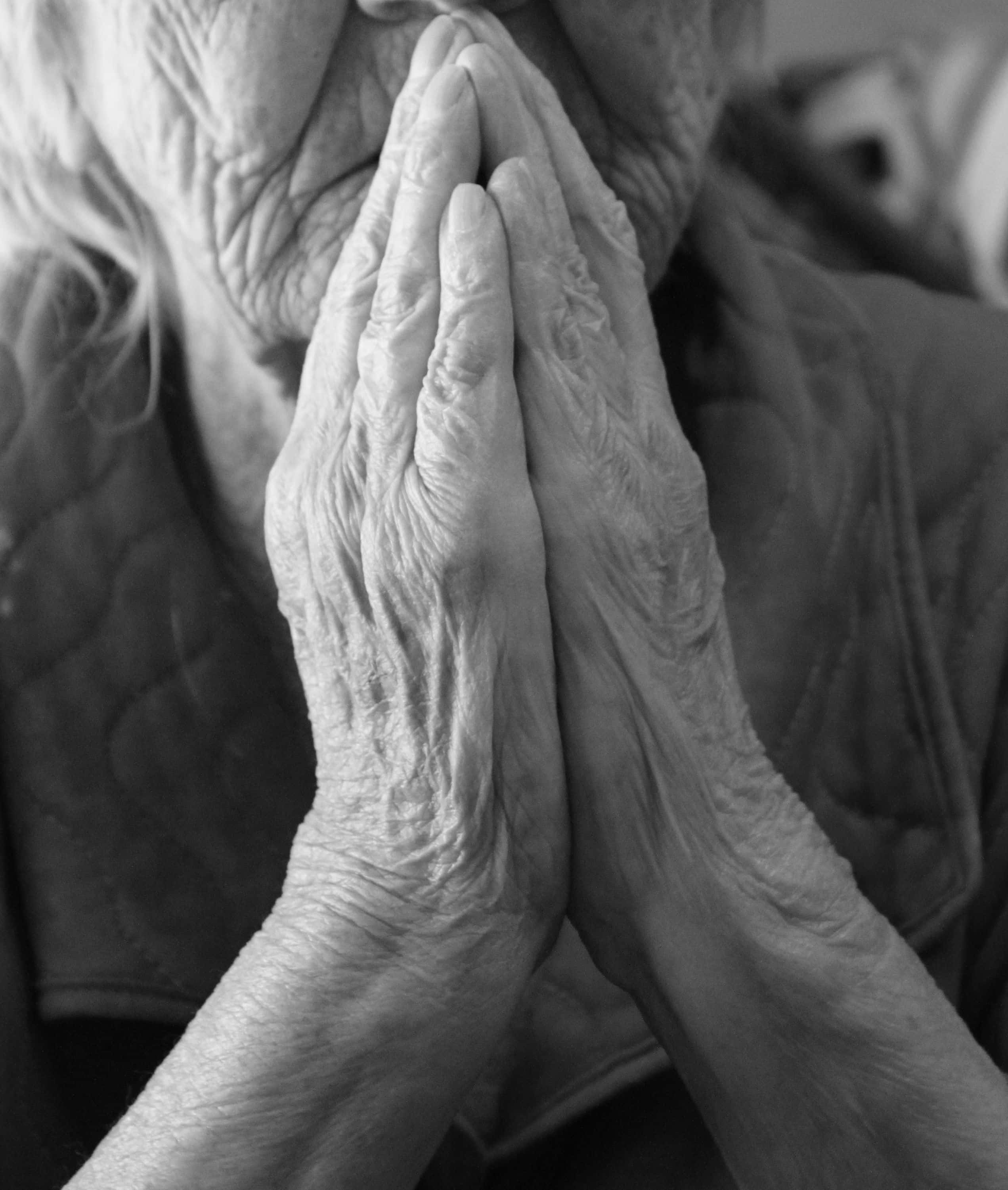 Praying 桌布 壁紙 — 一張黑白特寫照片，拍攝一位長者滿是皺紋的雙手在臉龐附近合十祈禱。