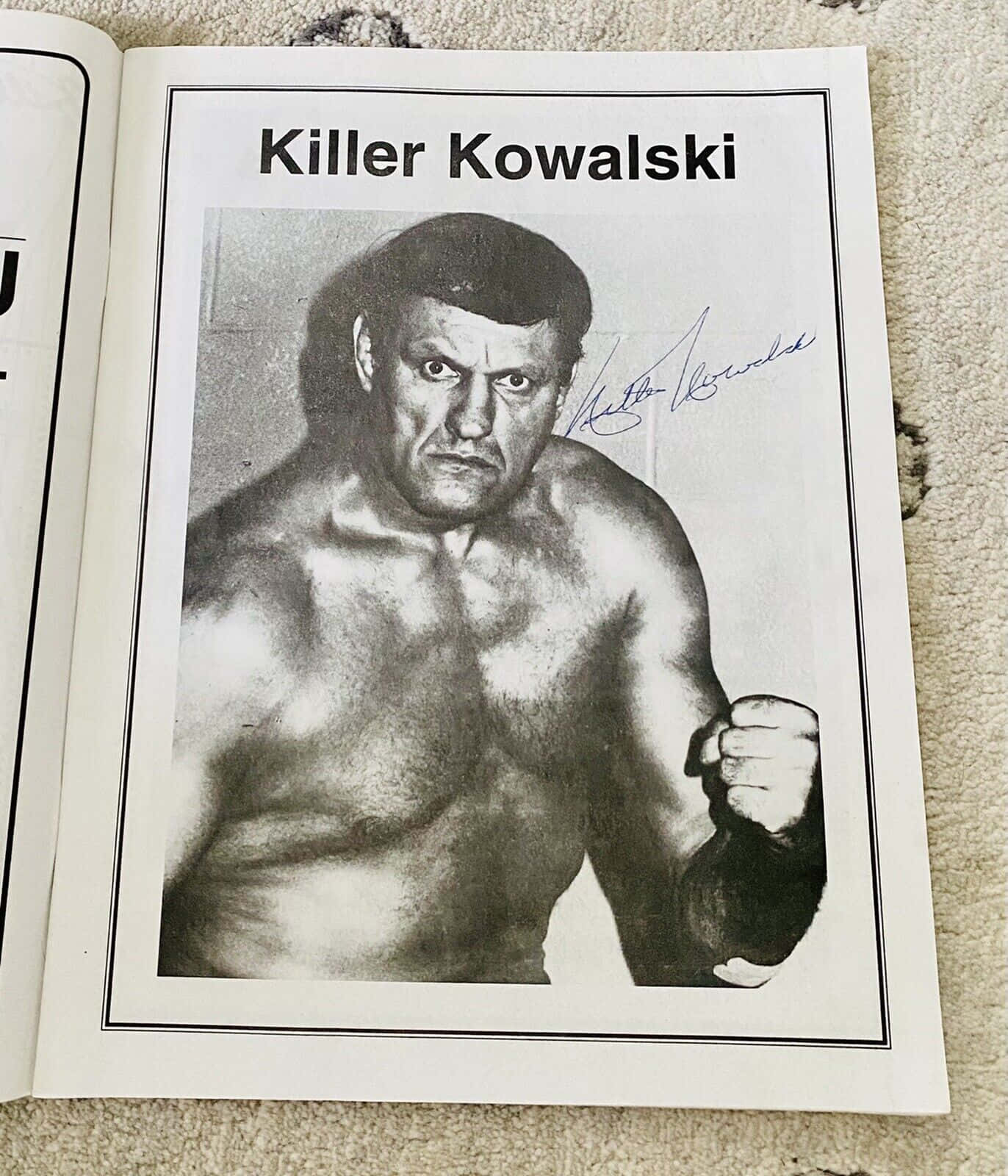 professional 桌布 壁紙 — 一張黑白簽名照片，摔角手Killer Kowalski在地毯上打開的書本內擺出威嚇姿勢。