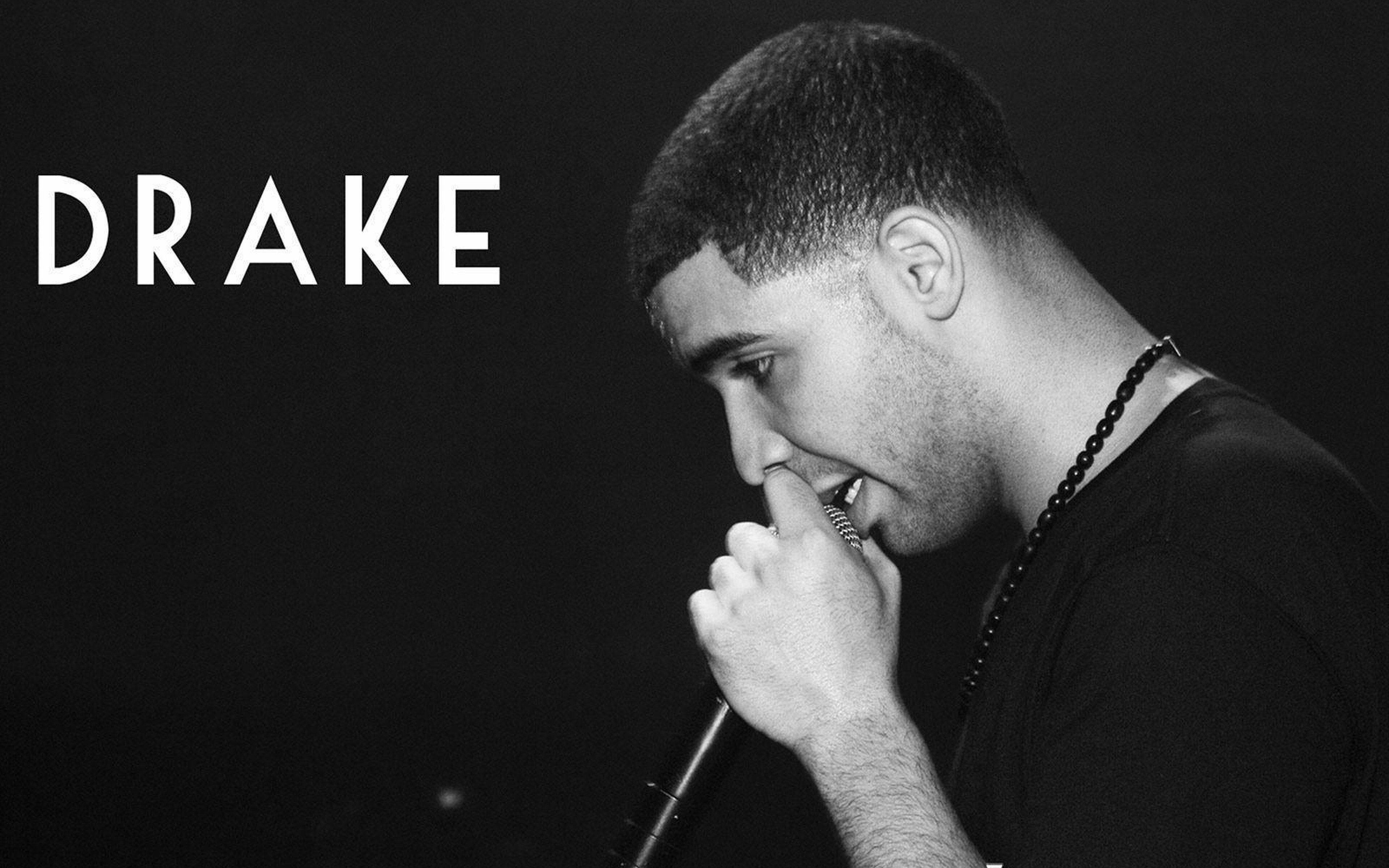 Drake 桌布 壁紙 — 一張黑白肖像，Drake 在黑暗背景下專注地對著麥克風唱歌。