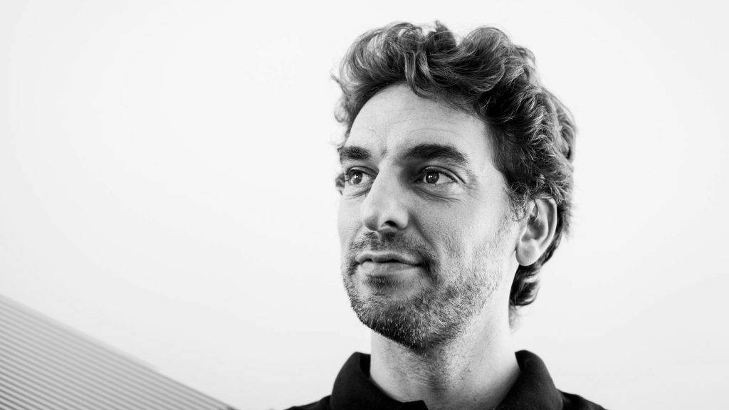 Pau Gasol 桌布 壁紙 — 一張黑白肖像，一名捲髮鬍鬚男子在極簡背景下若有所思地向上看。