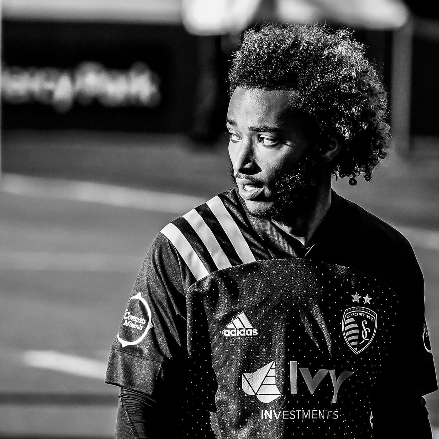 Athletic 桌布 壁紙 — 一張黑白肖像，描繪一位身穿 Sporting Kansas City 球衣的足球運動員，專注地望向一旁。