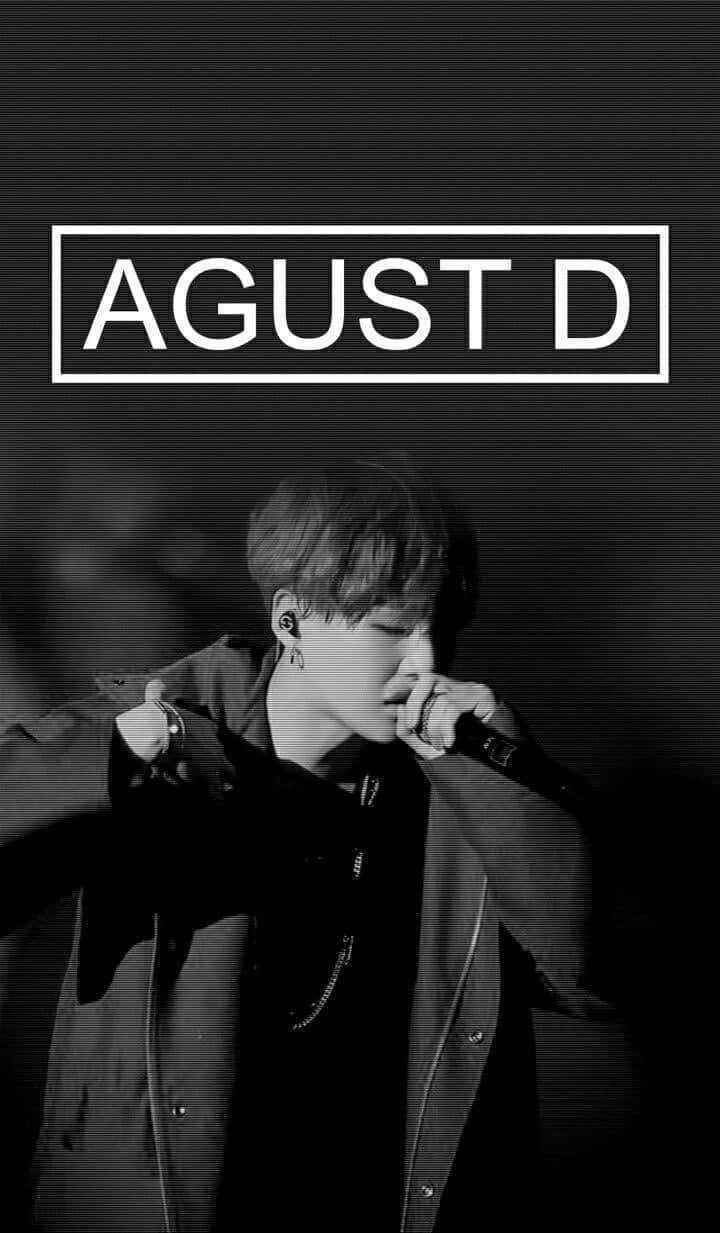 Agust D 桌布 壁紙 — 一張黑白肖像照，男歌手在深色紋理背景前手持麥克風表演，並疊加 'AGUST D' 文字。