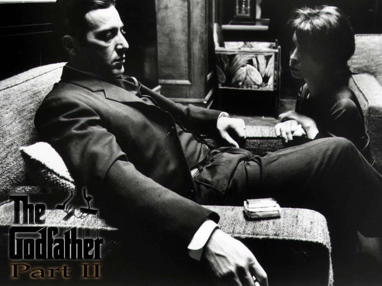 The Godfather 桌布 壁紙 — 一張黑白電影劇照顯示，一名身穿西裝的男子在光線昏暗的房間裡懶洋洋地躺在沙發上，而一個小男孩坐在他旁邊。