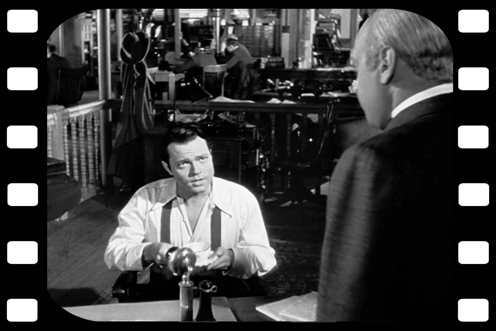 Citizen Kane 桌布 壁紙 — 一張黑白電影劇照顯示一名穿著襯衫和吊帶褲的男子坐在辦公桌前，面對另一名穿著西裝的男子，場景在辦公室內。