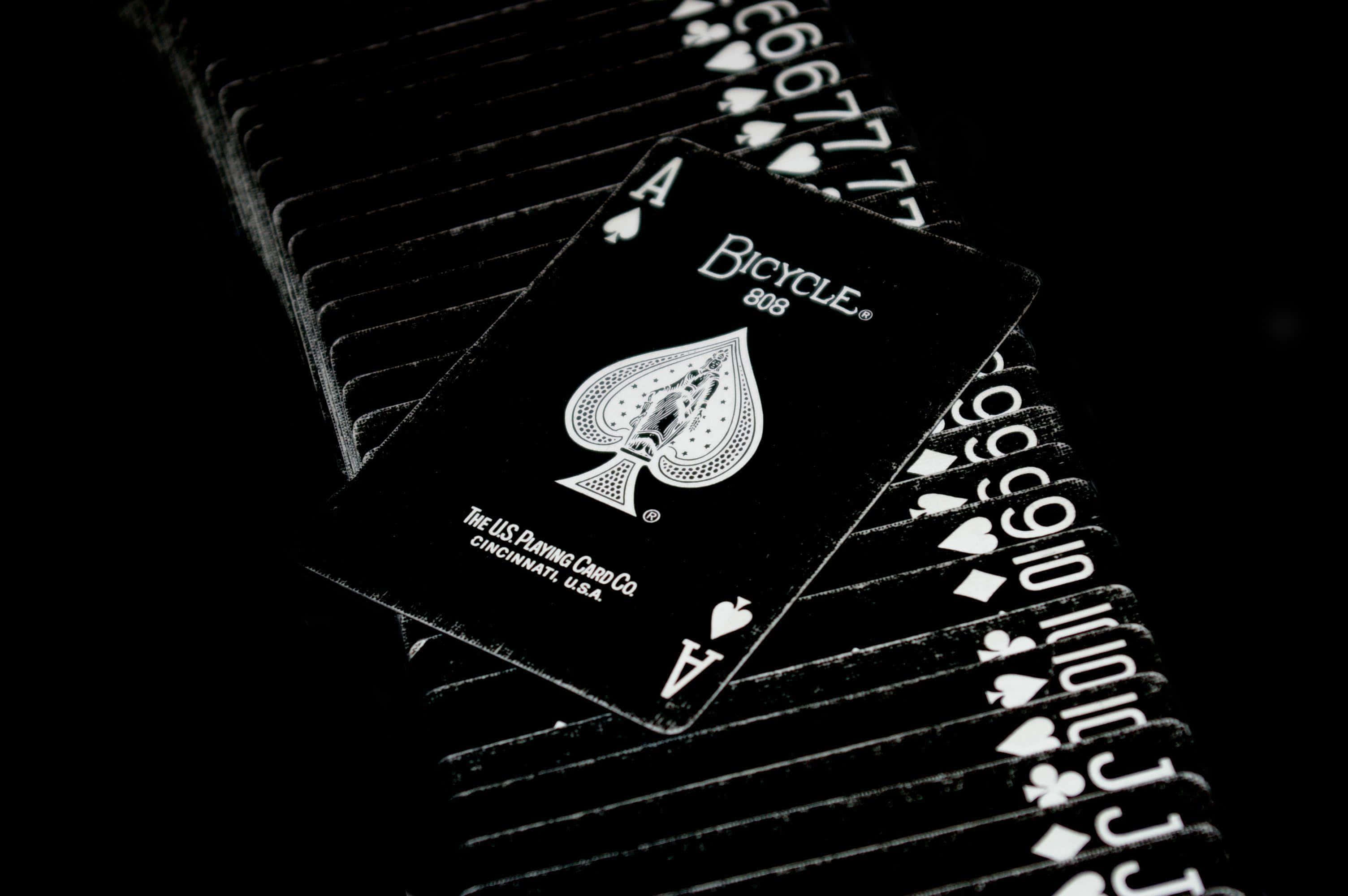 Card Games 桌布 壁紙 — 一張黑色Bicycle黑桃Ace牌放在深色背景前扇形展開的撲克牌堆上。