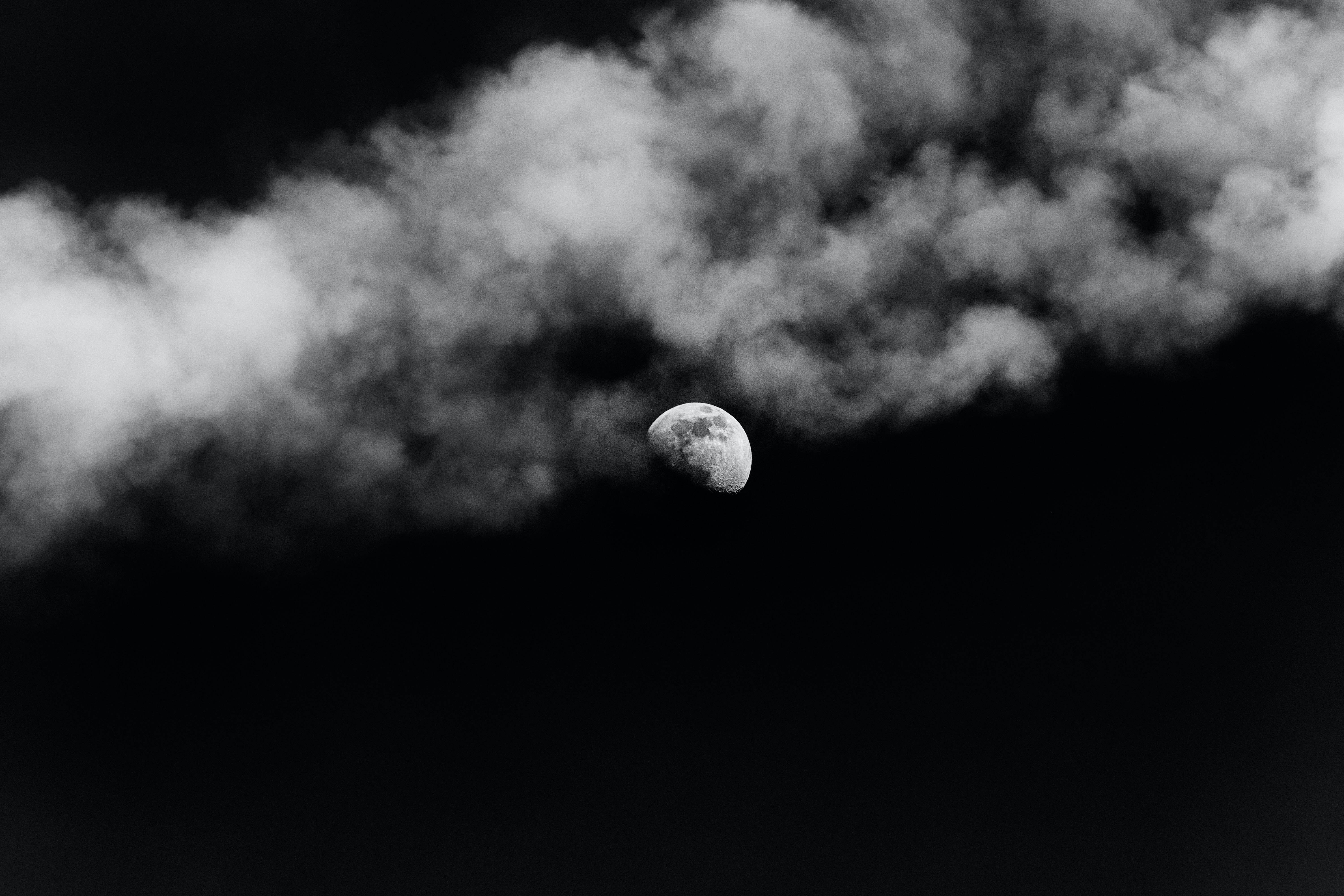 雲朵 桌布 壁紙 — 一彎單色新月從縷縷雲層中窺視，映襯著深邃的黑色天空。