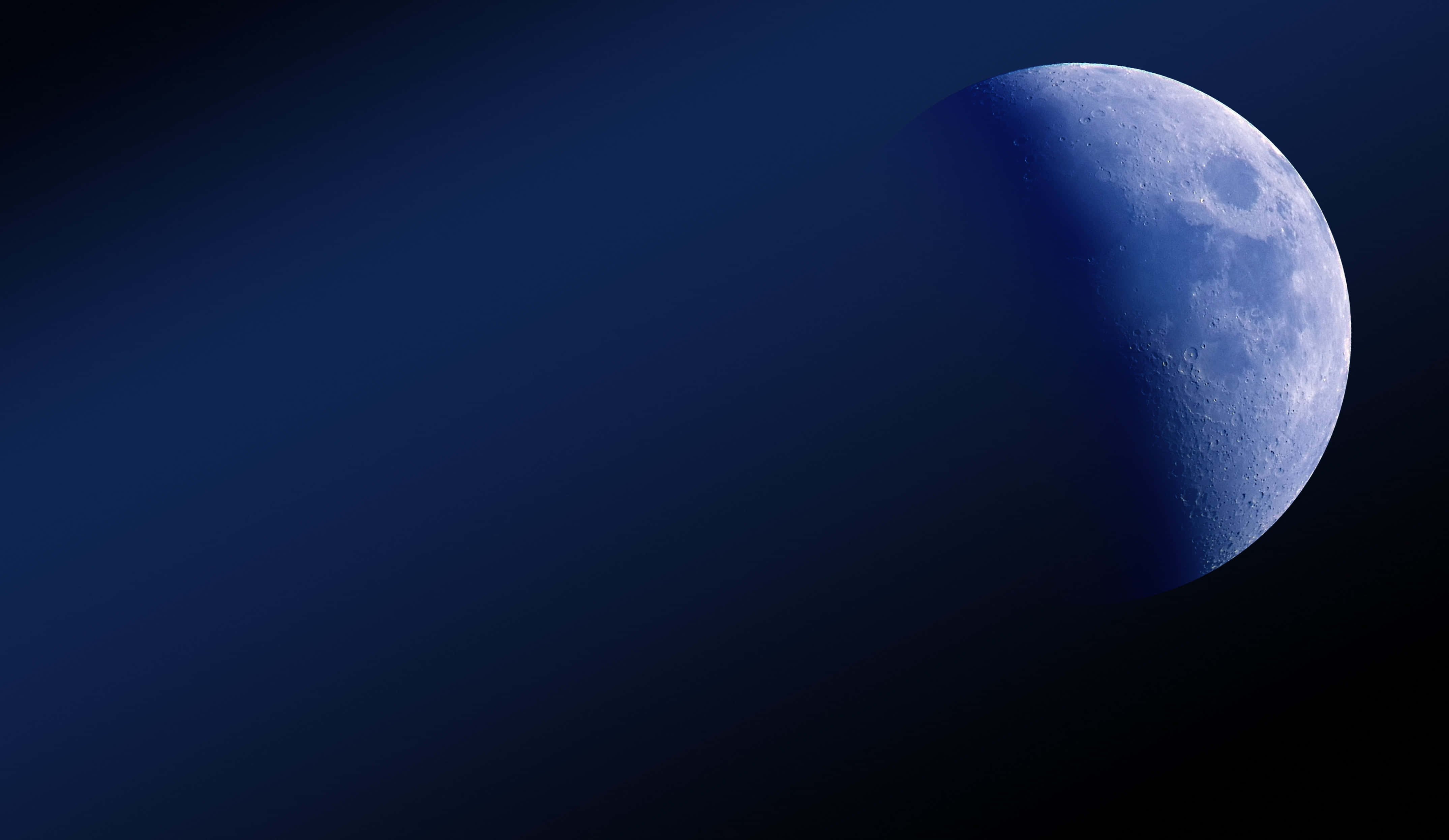 Half Moon 桌布 壁紙 — 一彎寧靜的弦月，在深靛藍與海軍藍的漸變夜空中柔和地發光。