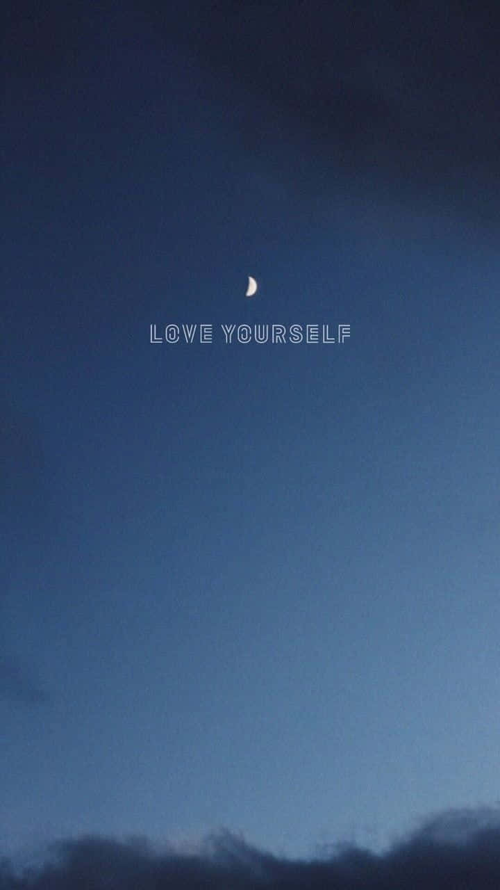 love yourself 桌布 壁紙 — 一彎新月在暮色天空中柔和發光，下方漂浮著愛自己這句話。
