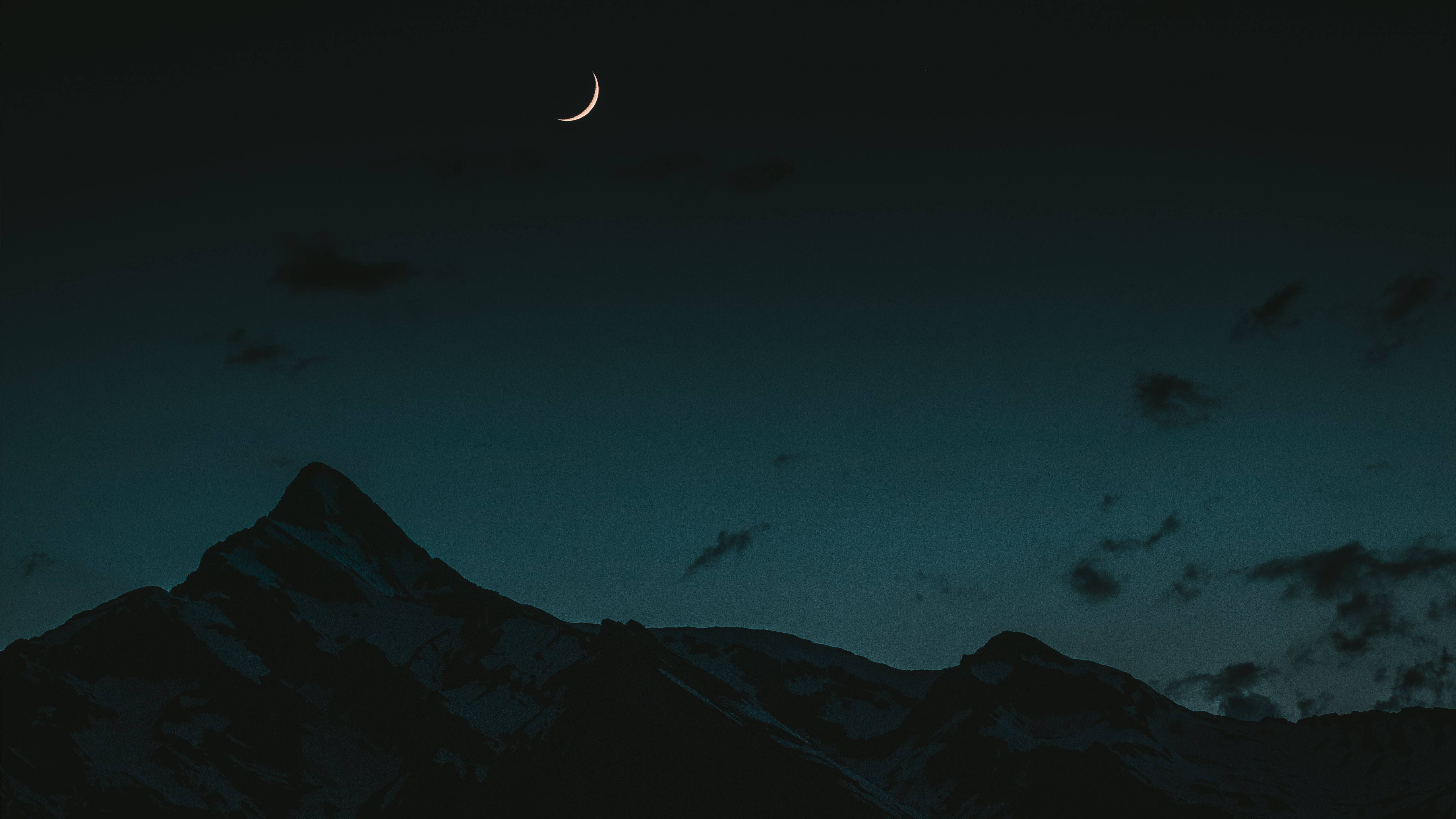 Crescent 桌布 壁紙 — 一彎新月在深 twilight 天空下，散雲點綴，照耀著積雪的山脈。