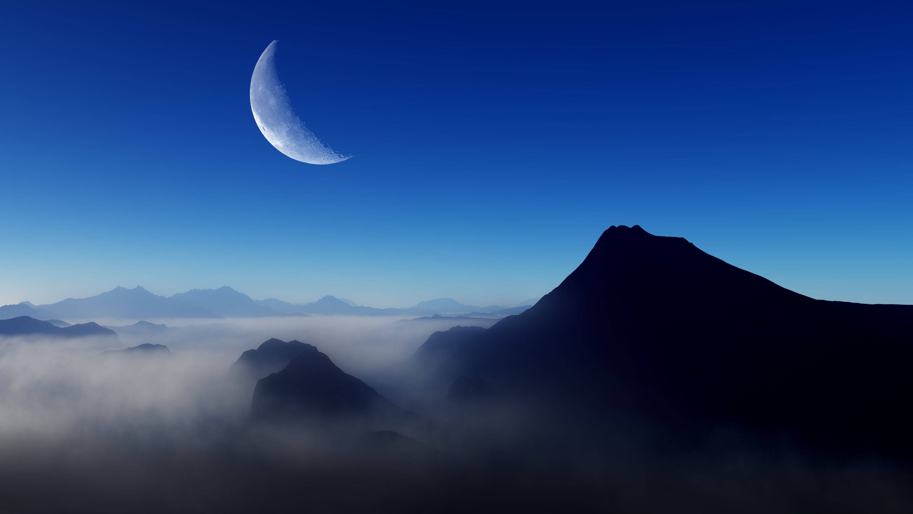 山景 桌布 壁紙 — 一彎新月在深藍色夜空下，從霧海中升起的鋸齒狀山峰上方發光。